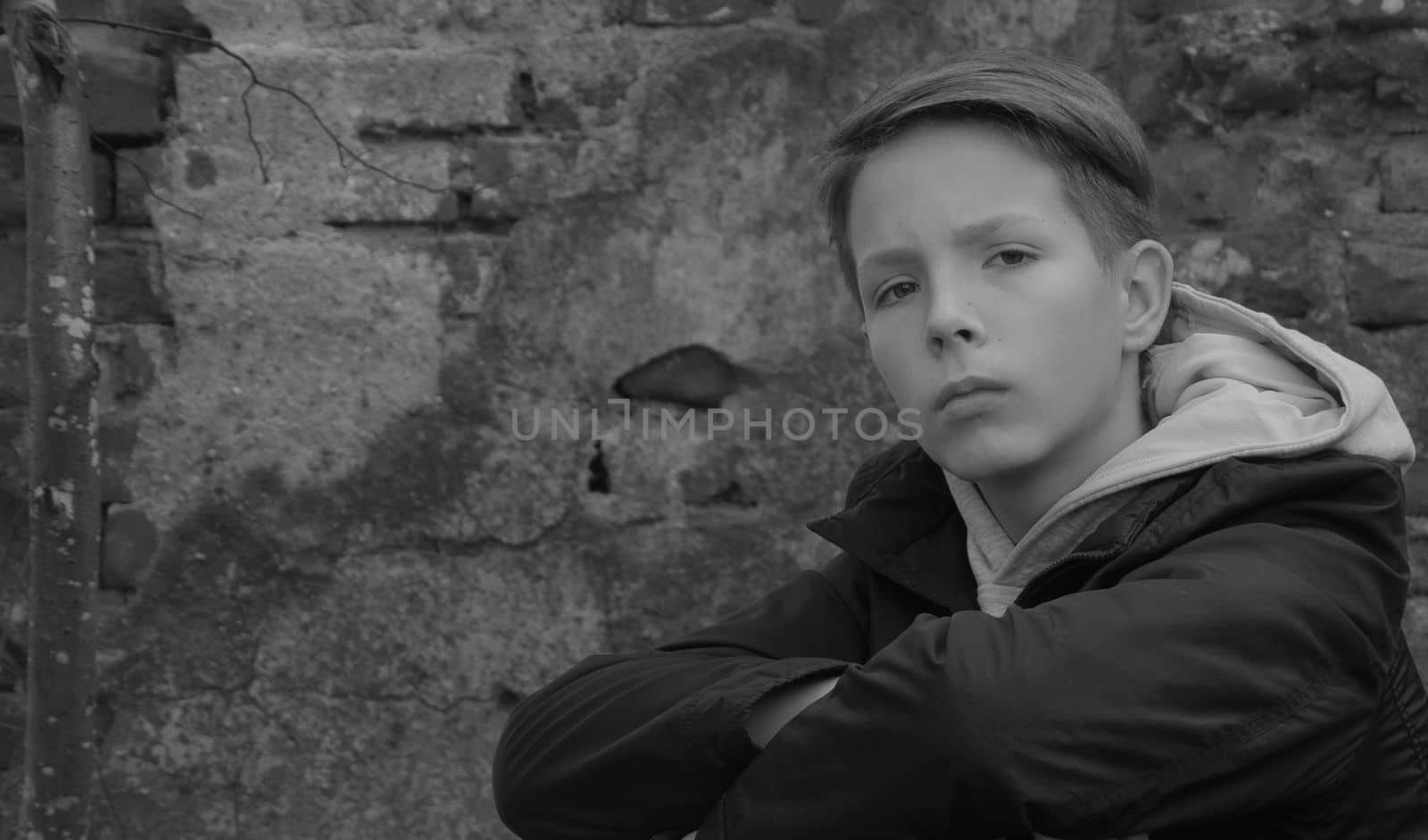 Beautiful boy with a serious look on the background of a red brick wall.A boy with a smart look looks at the camera.