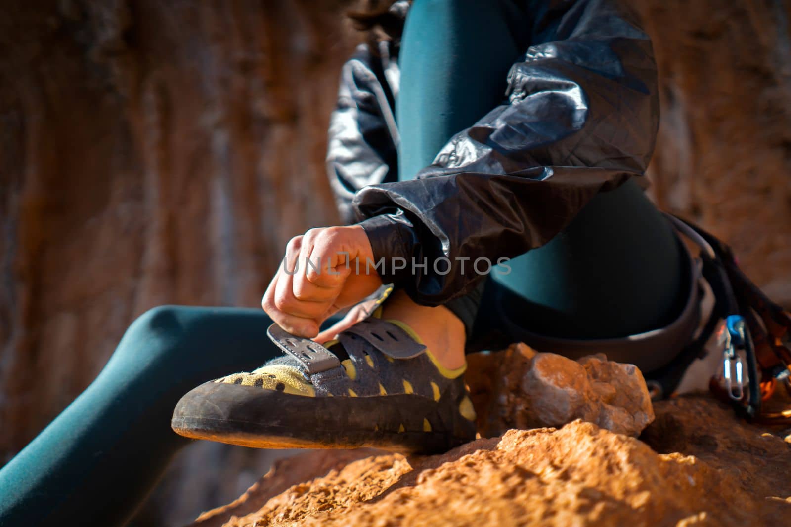 A young girl puts on special climbing shoes on her legs before climbing outdoor training, hands and feet close-up. A woman leads an active lifestyle, is involved in mountaineering and rock climbing.