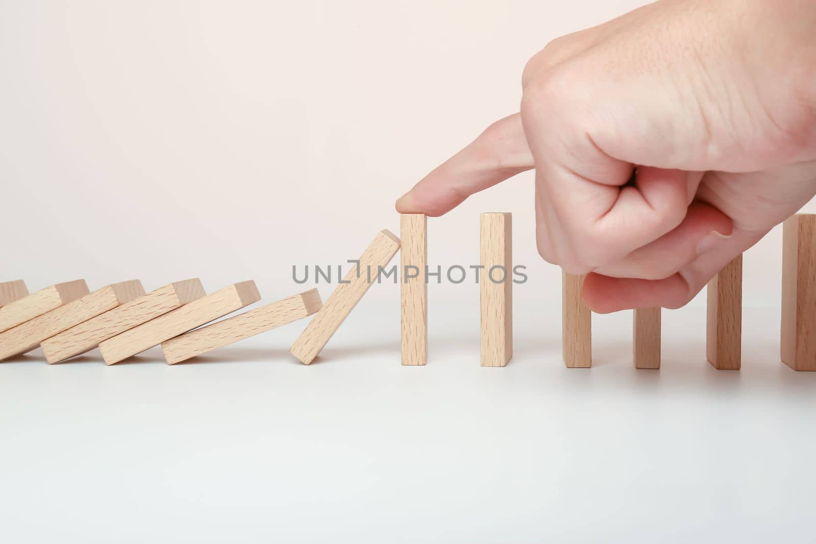 Hand stopping the Domino effect stopped by unique, Business Ideas