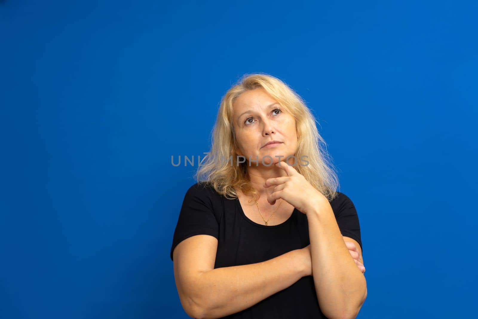 Portrait of cunning curious emotion expressing frankness pretty charming with blonde hair pensive woman planning weekend vacation in black t-shirt isolated on blue background