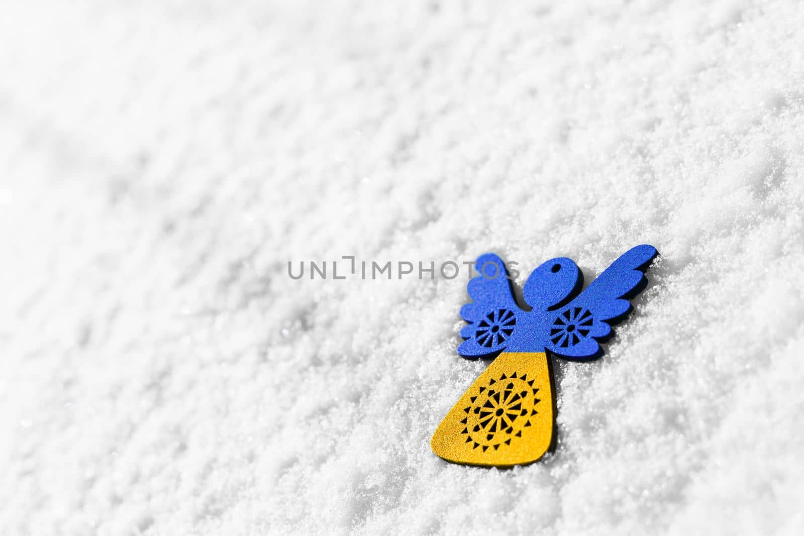 blue and yellow toy angel on white snow by alexxndr