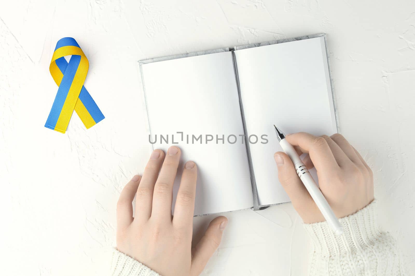 hands with blank notepad and ukraine ribbon by alexxndr
