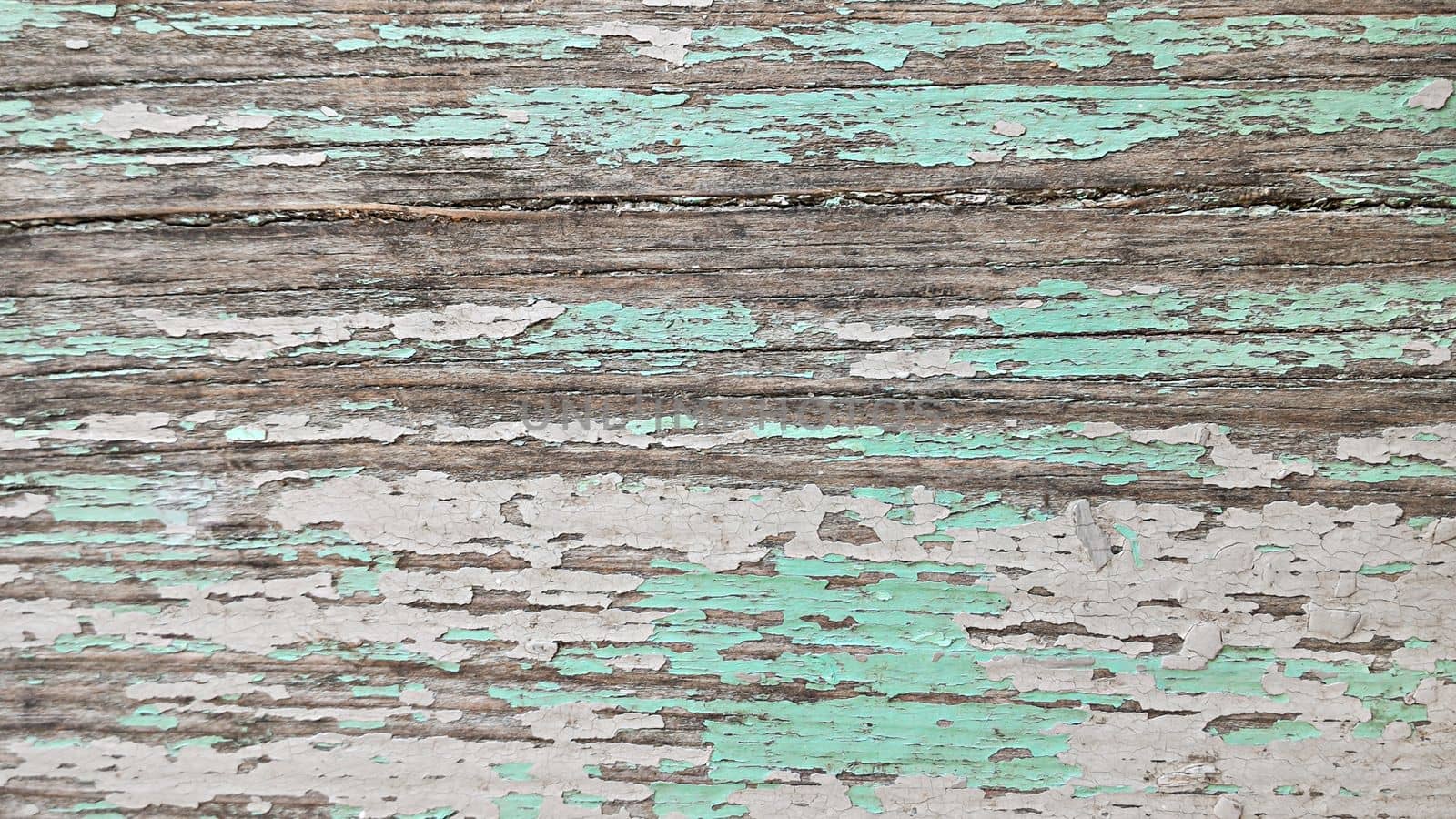 Wooden surface with cracked multi-colored pastel paint. Top view