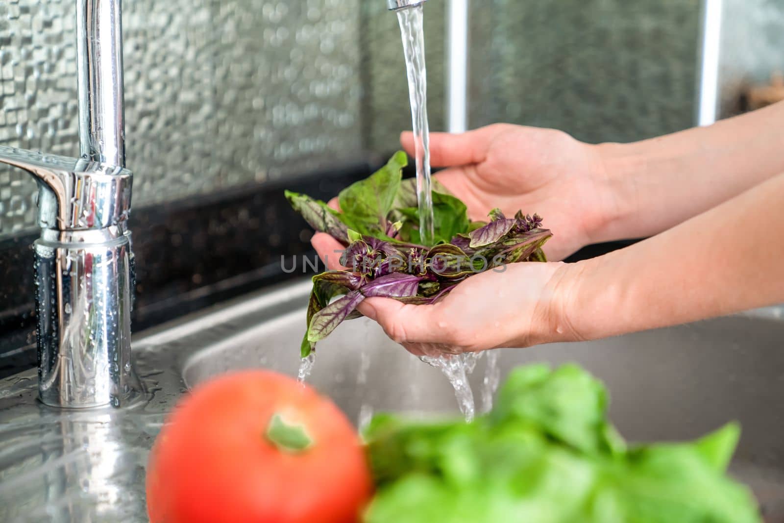 Woman washes fresh vegetables over sink, close-up by Laguna781