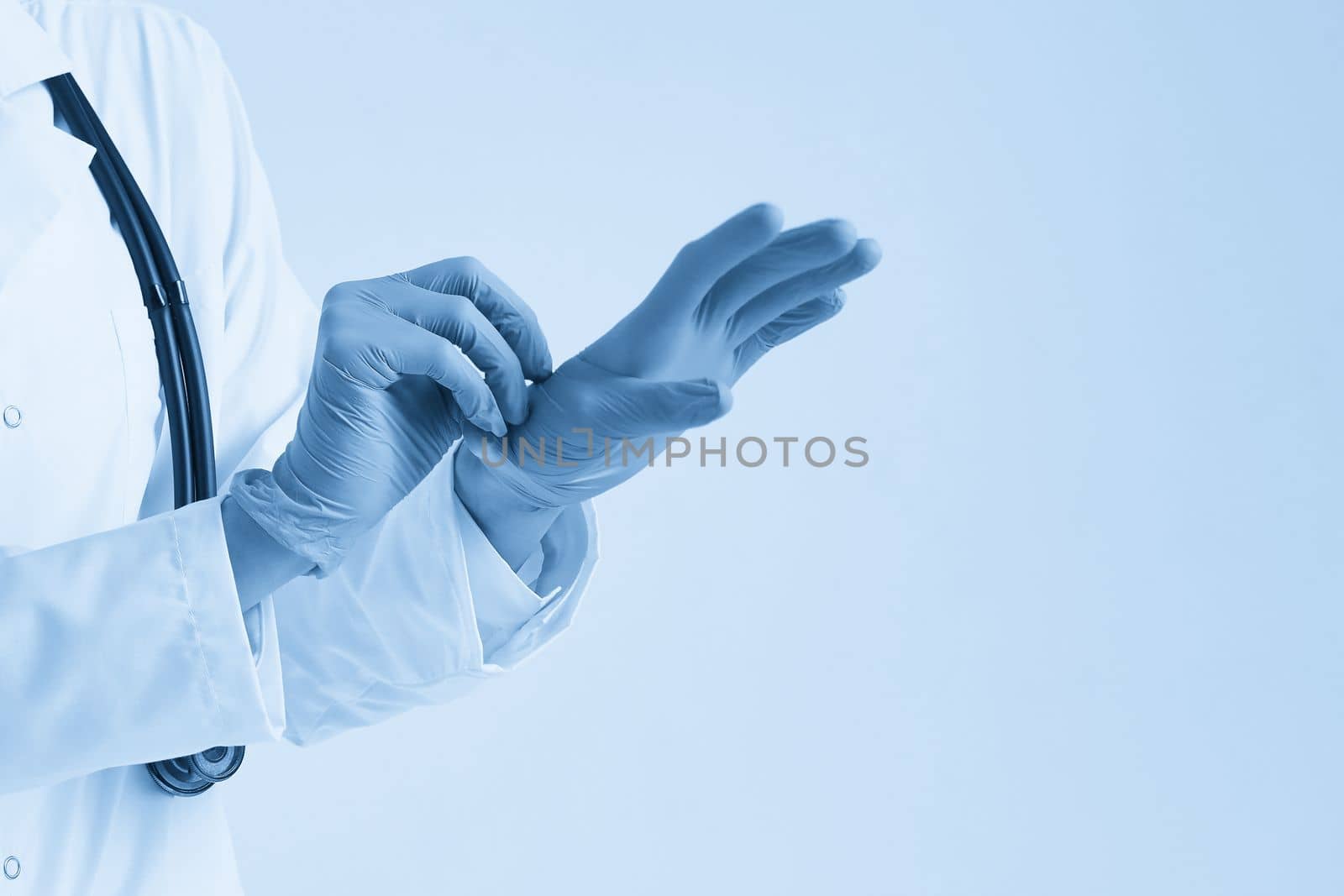 Young doctor putting on surgical gloves over white background by Mariakray