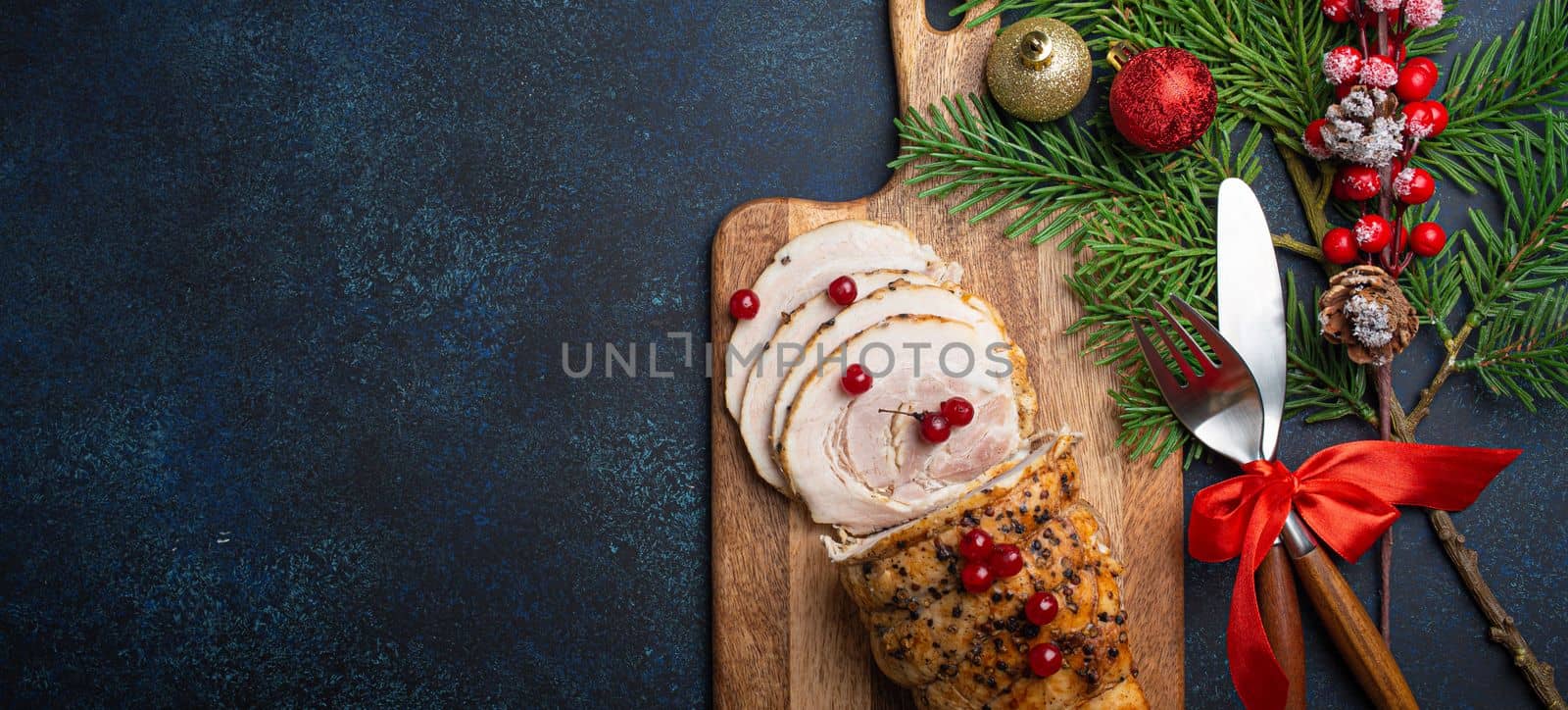 Christmas baked ham sliced with red berries and festive decorations by its_al_dente