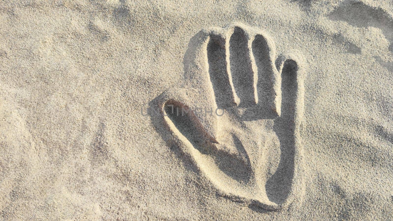 Background of handprint in sand, copy space. Top view, close-up