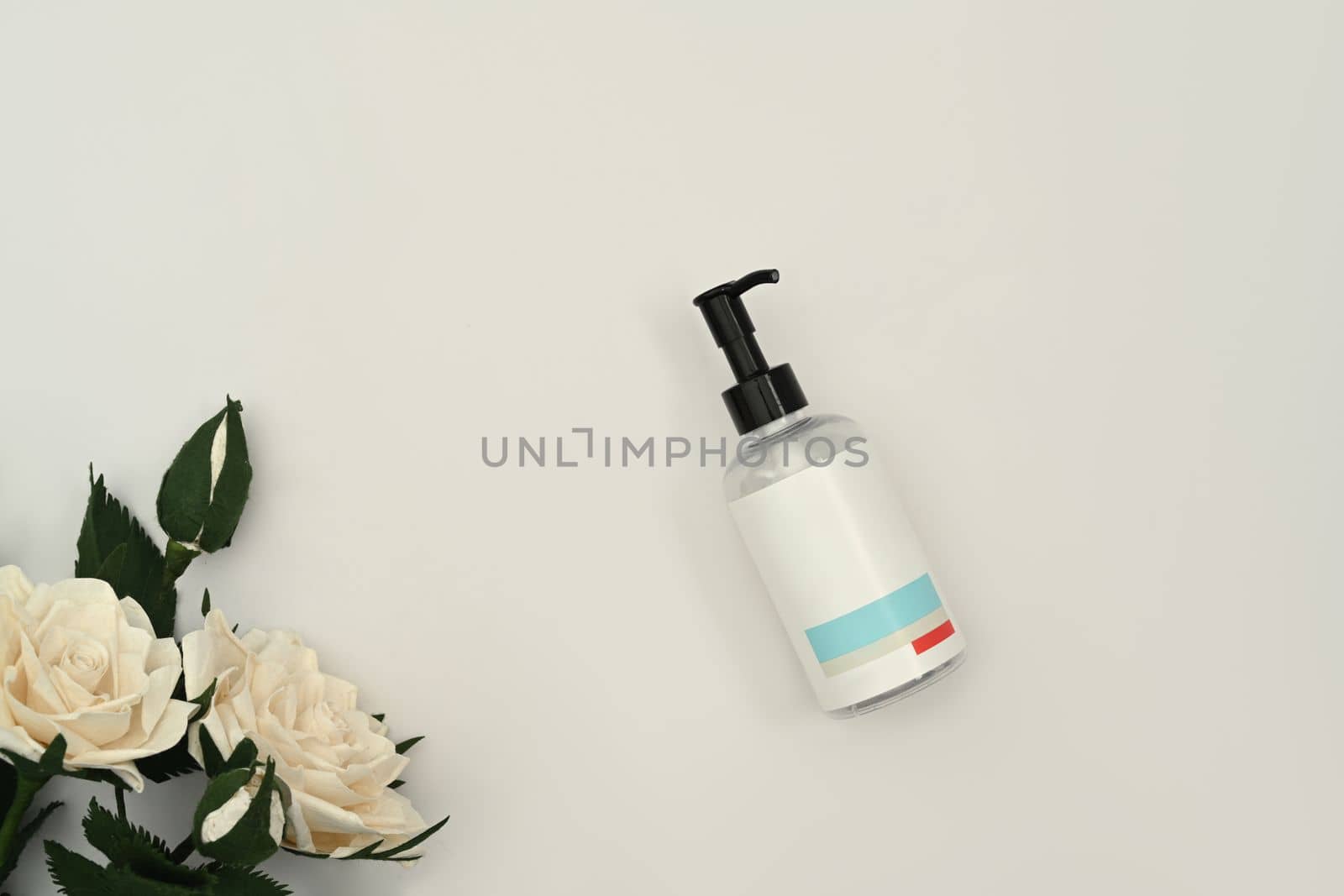 Shampoo or soap plastic bottle dispenser with white rose on white background. Natural skincare, beauty product design concept by prathanchorruangsak