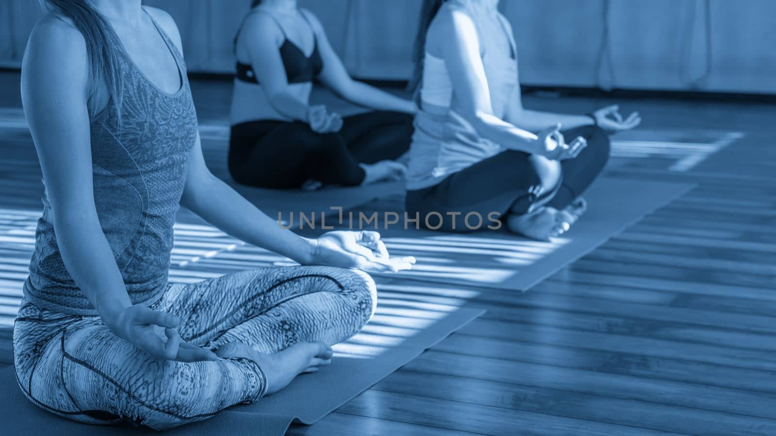 young women in yoga class sitting and relaxing making meditation lotus pose by Mariakray
