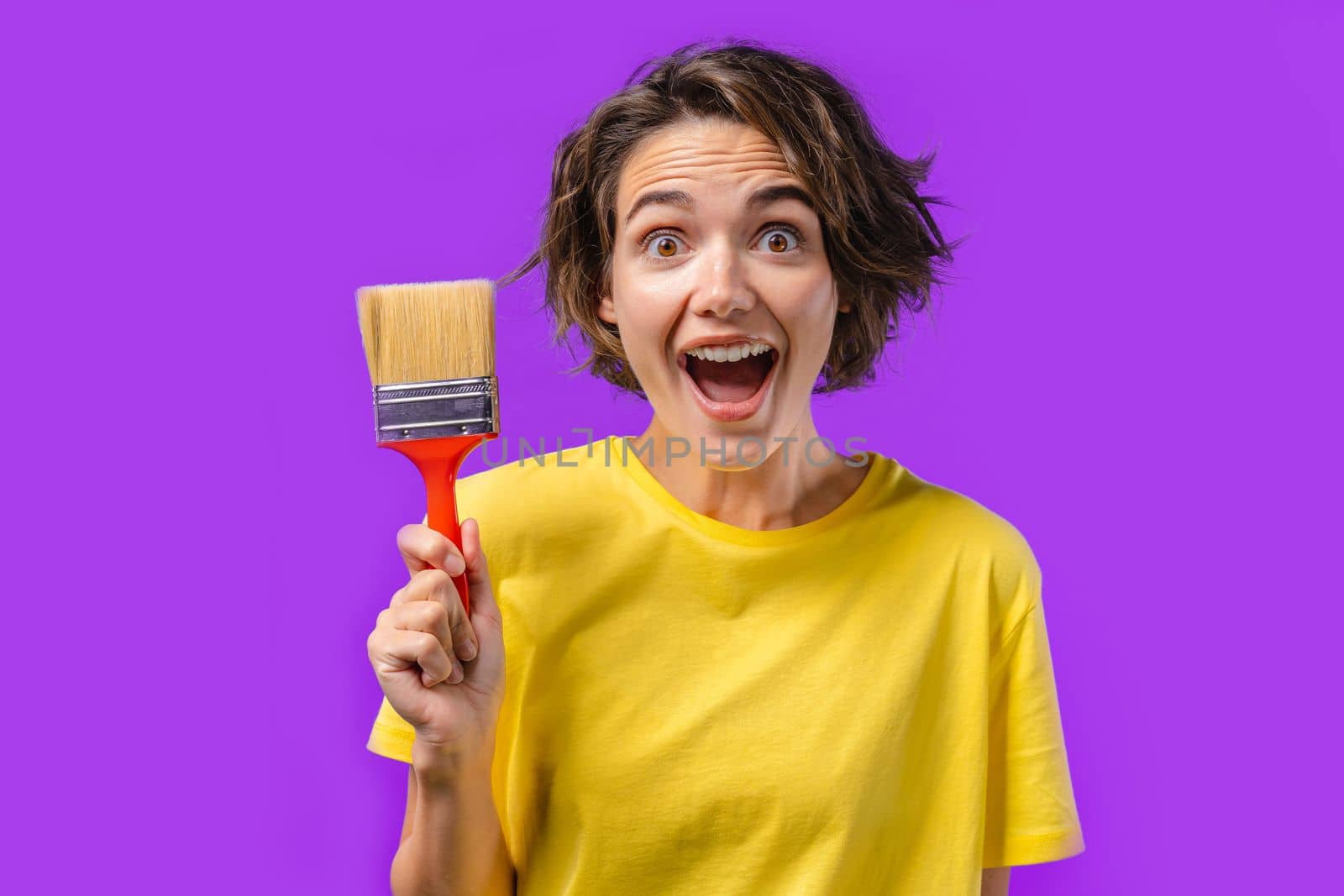Happy woman artist with painting brush on violet background. Creative person, fantasy, idea, non-standard approach to life, repair in apartment. High quality photo
