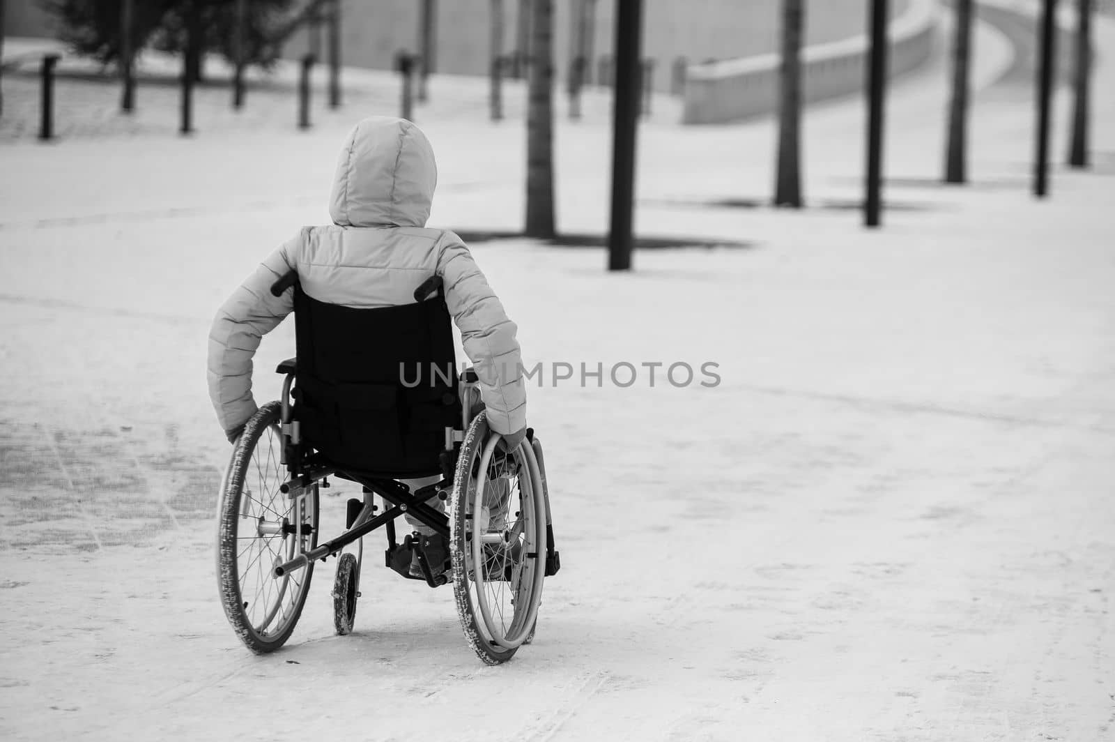 Homeless woman sits in a wheelchair in winter. black and white