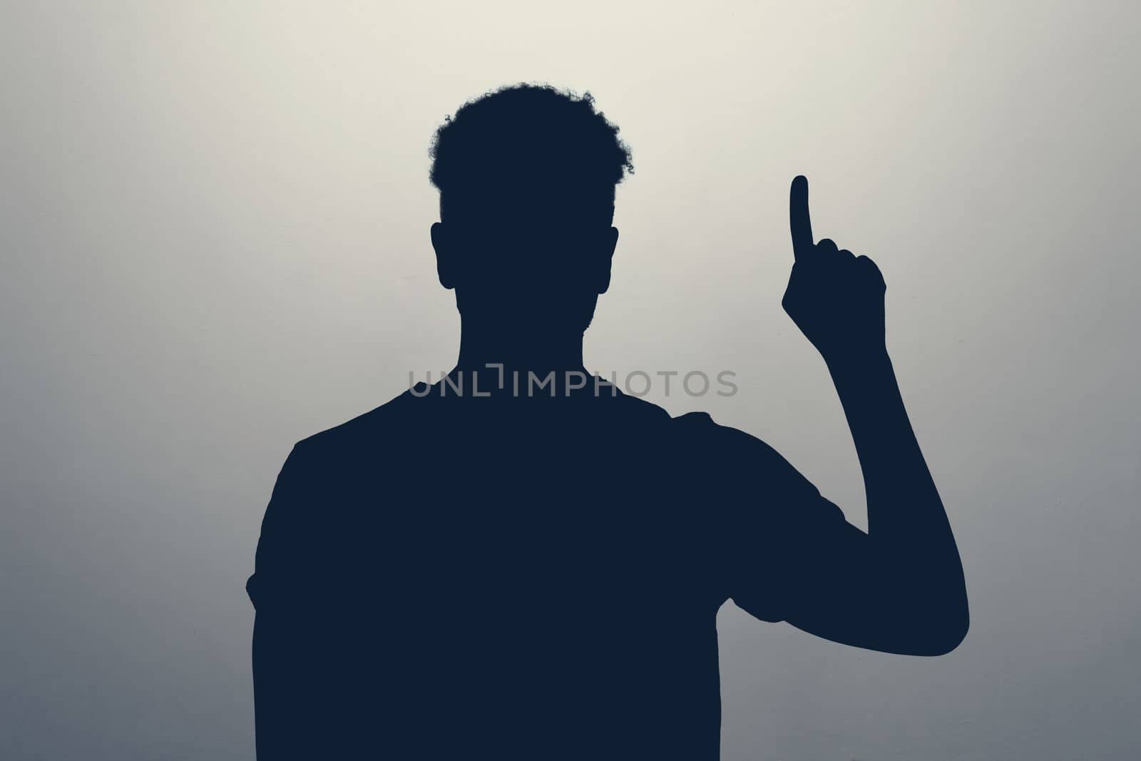 silhouette of man pointing up with his finger isolated on gray background. Pay attention here