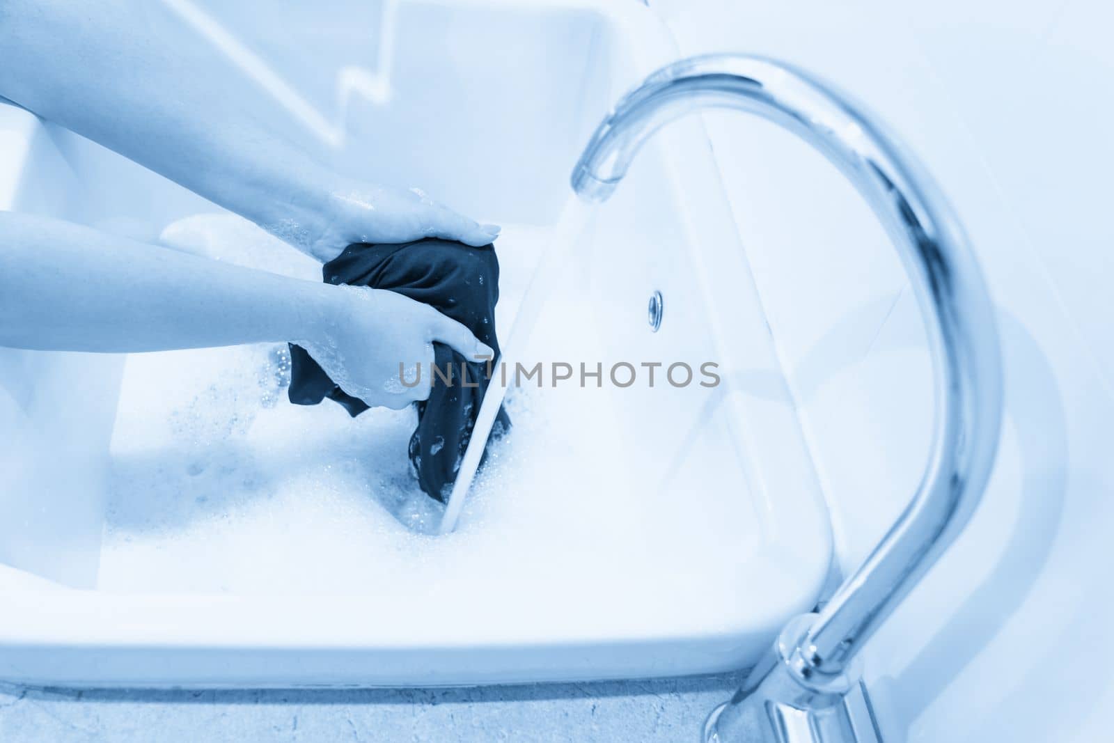 Female hands washing color clothes in basin