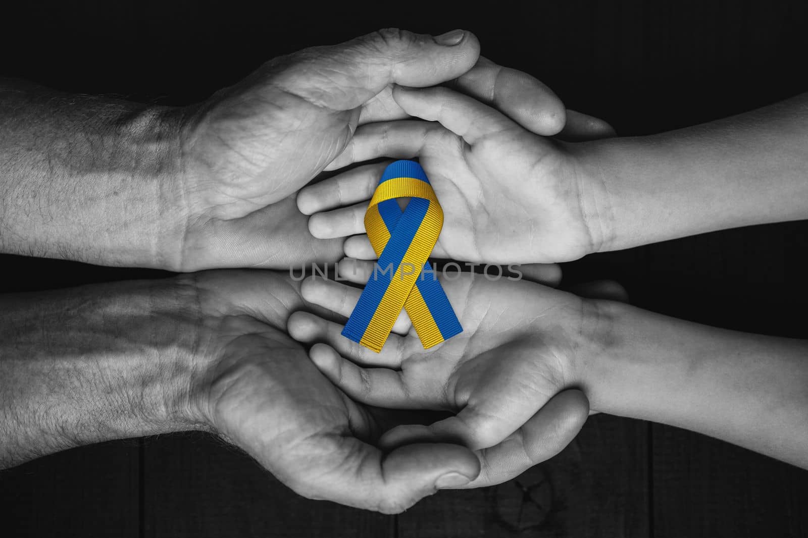 children hands in male hands with ukraine ribbon by alexxndr