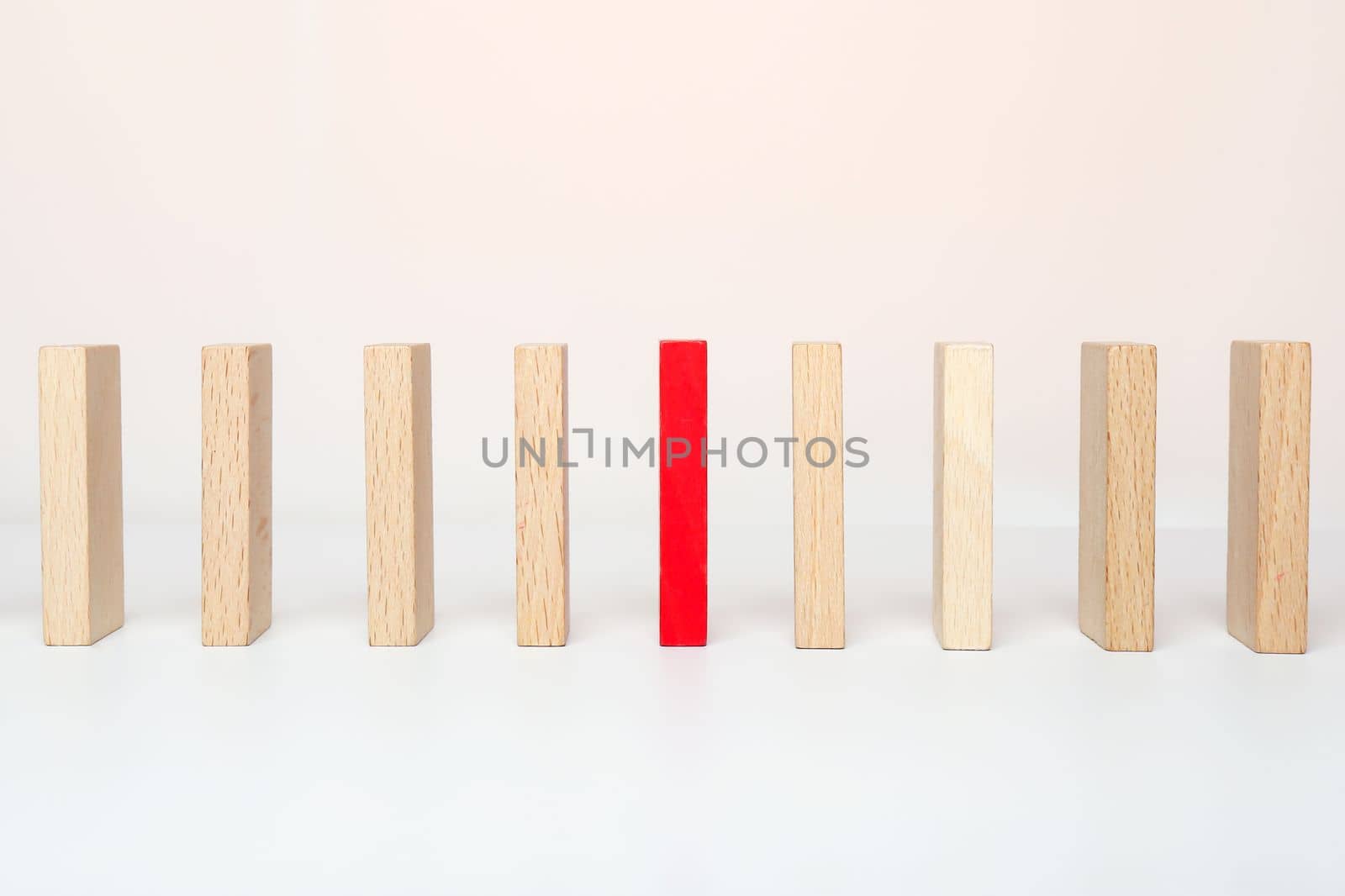 One red wooden block between the wooden block on white background. Be different concept.