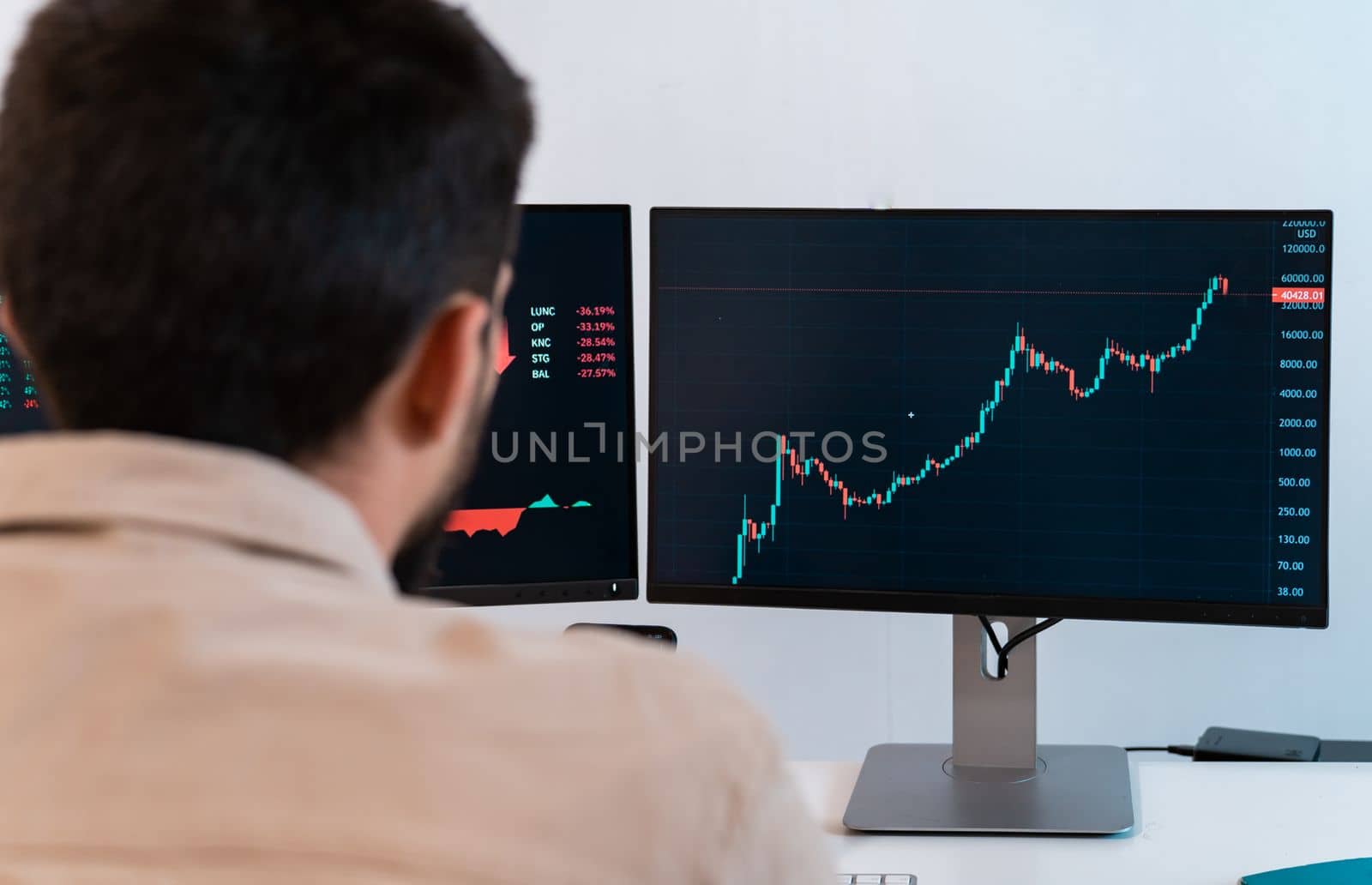 Young caucasian male finance broker analyzing stock graphs while trading from modern home office. by PaulCarr