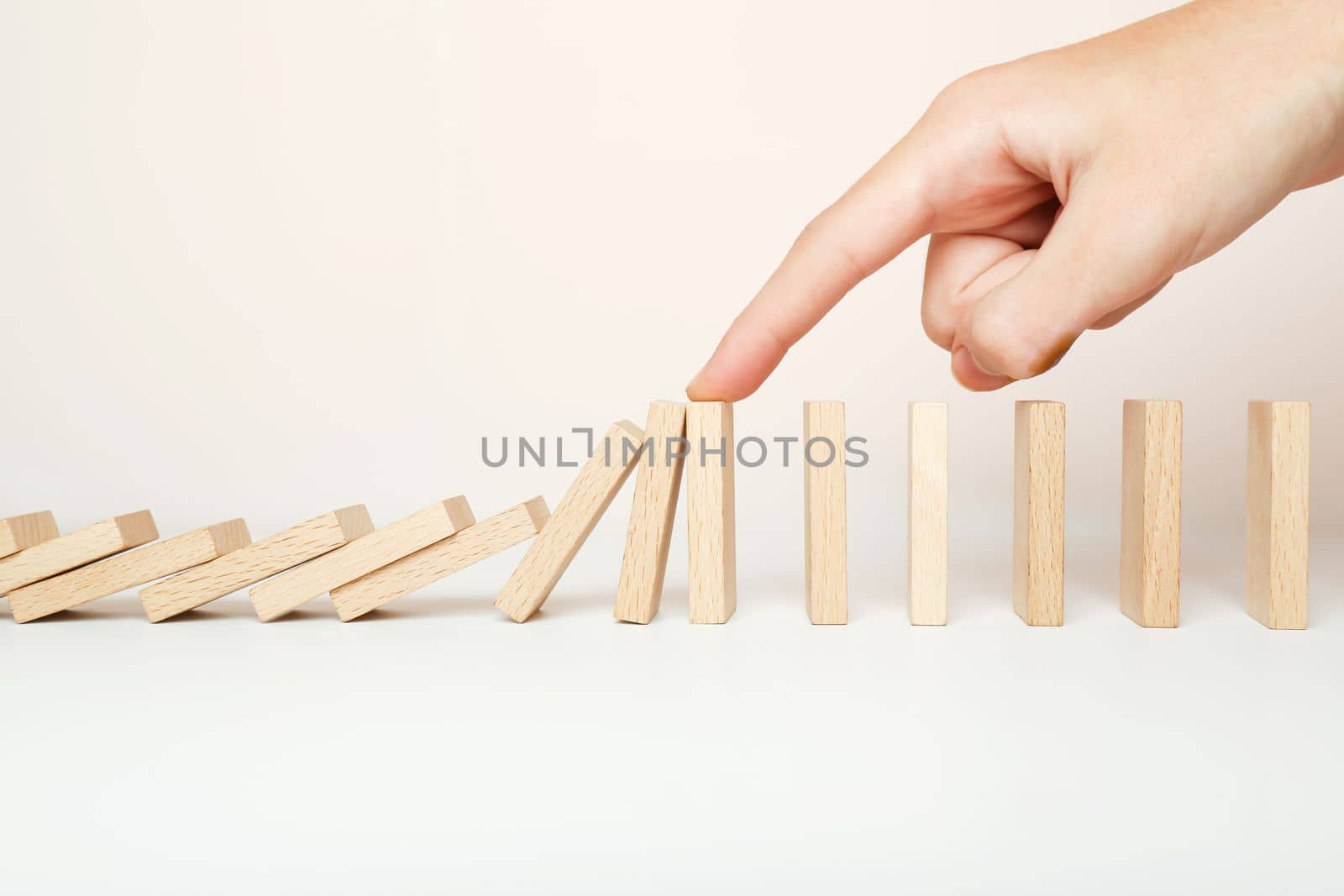 Hand stopping the Domino effect stopped by unique, Business Ideas