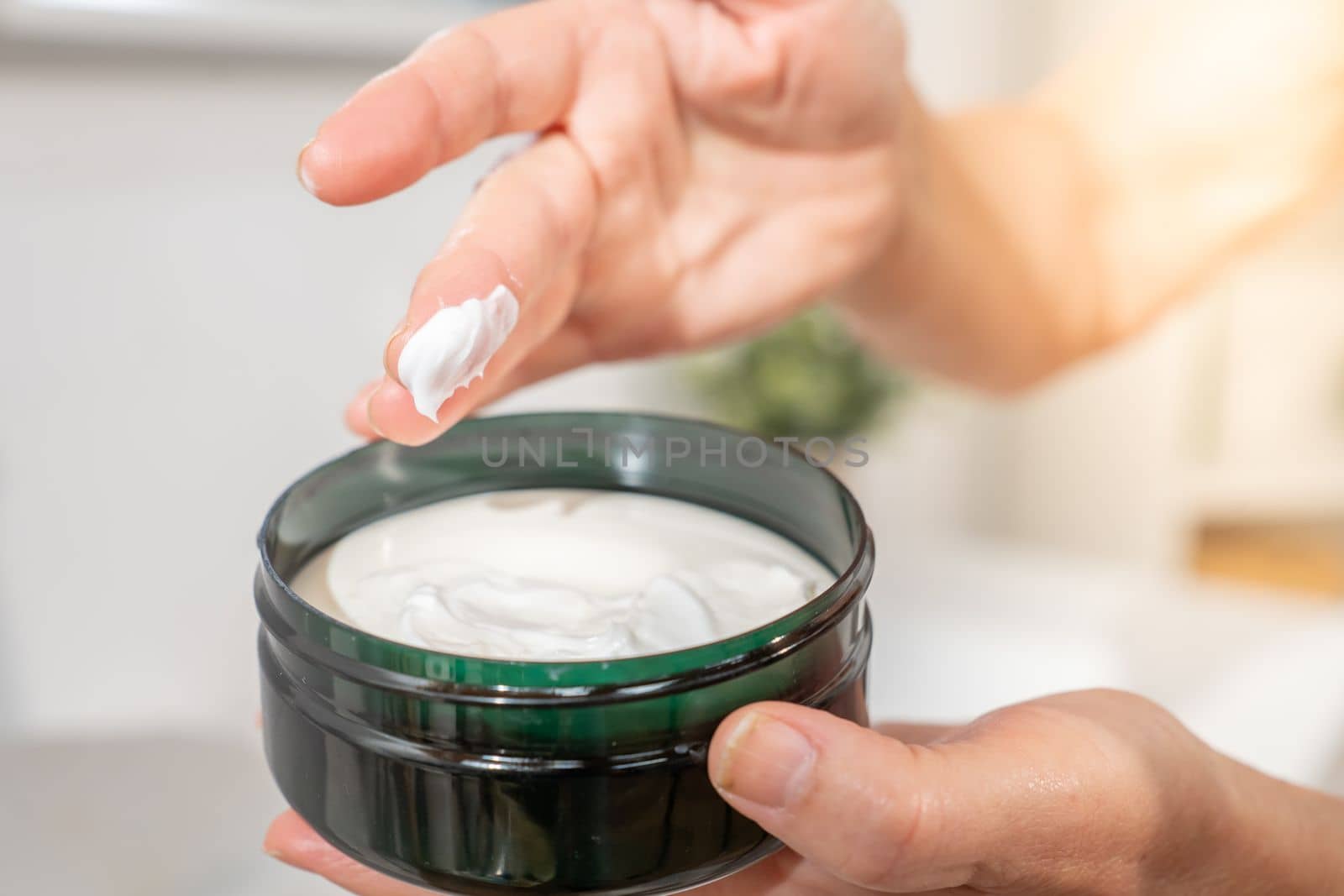 Closeup of a hand of a middle-aged woman smearing her finger with cosmetic cream for skin care and beauty. anti-aging anti-wrinkle concept