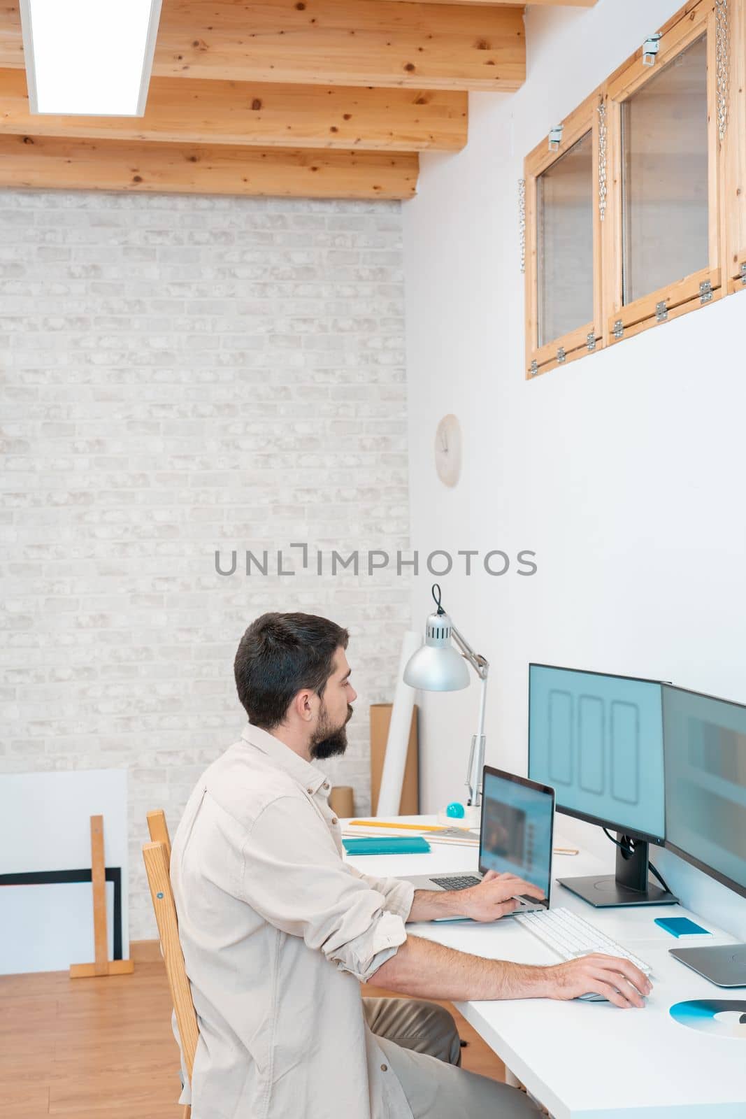 Vertical shot of a young entrepreneur working in his computer in a modern workspace office at home. Freelance guy starting small business. High quality photo