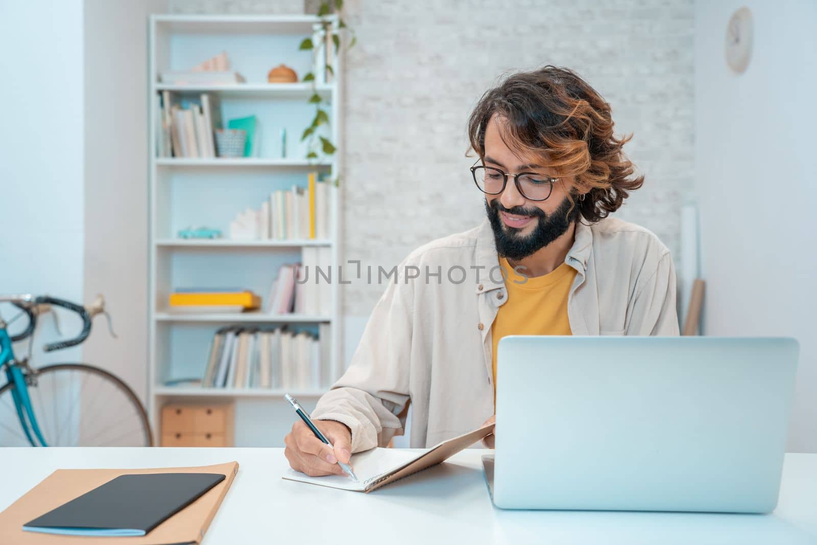 Man using laptop at home remote work in a small business. Handsome smiling male freelancer entrepreneur working in a creative project with research. High quality 4k footage