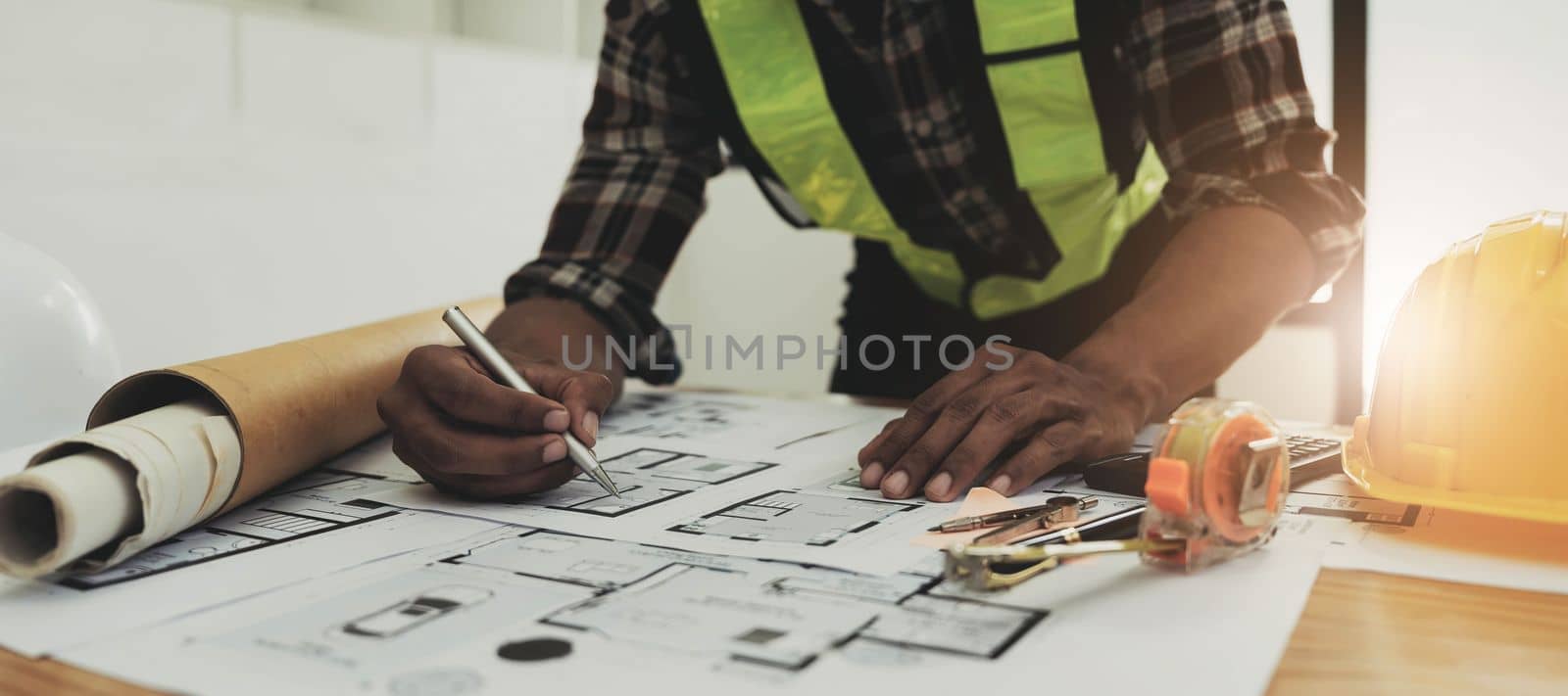 Close up of civil male engineer asian working on blueprint architectural project at construction site at desk in office