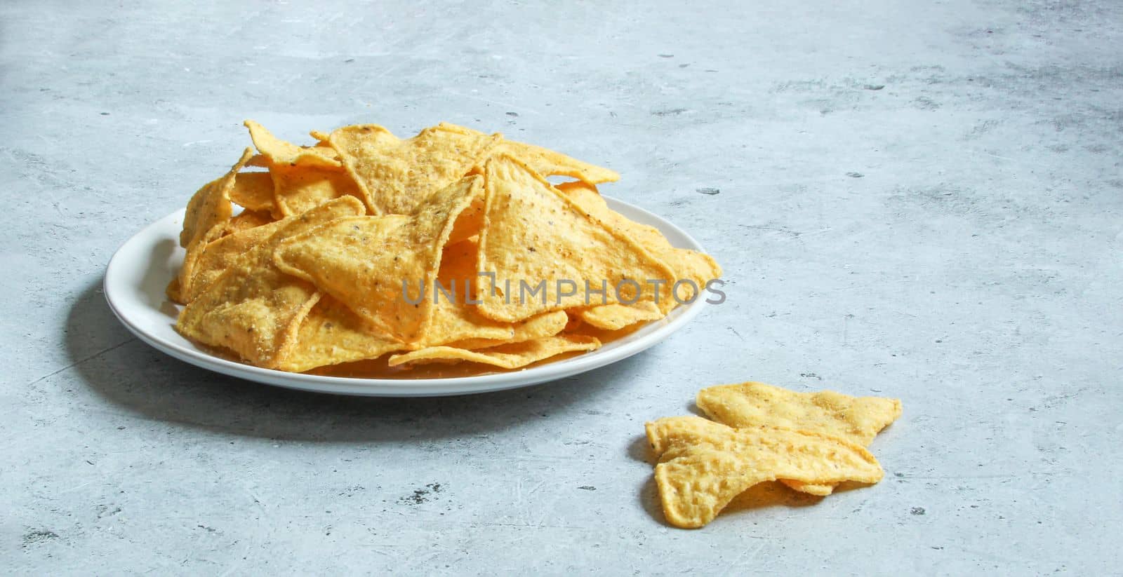White plate with corn chips nachos on the concrete background. Mexican nachos. by IrinaKur