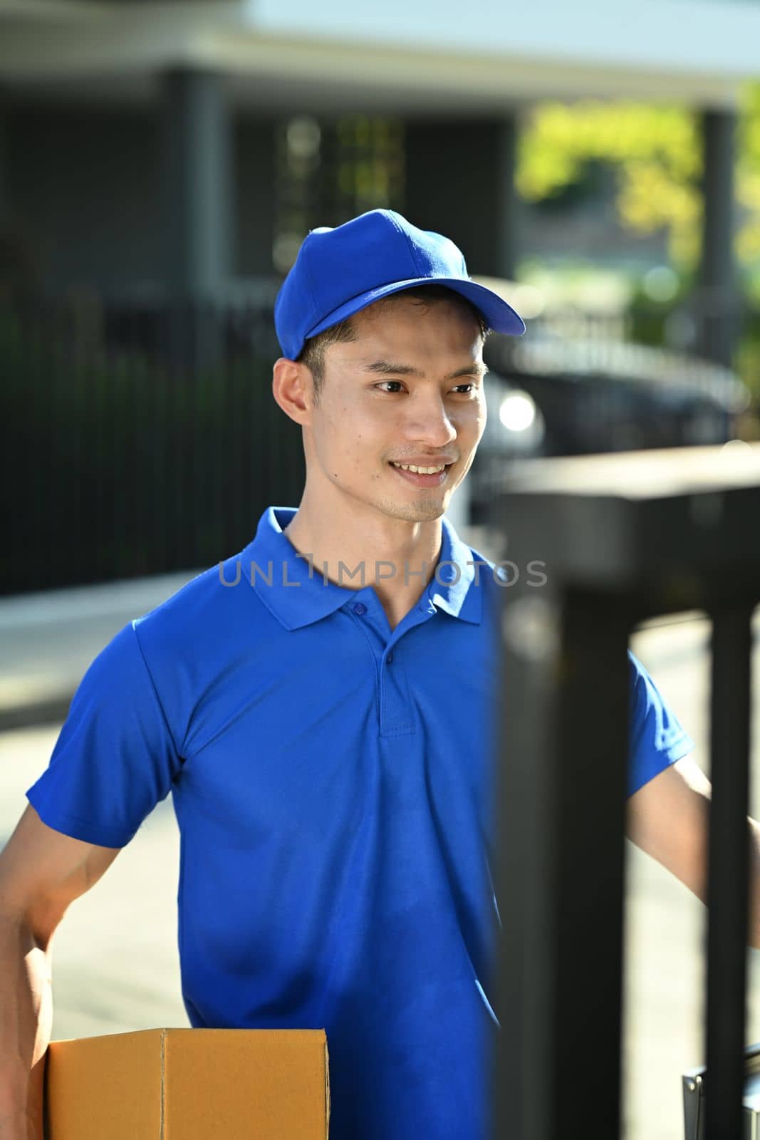 Delivery man holding cardboard box and ringing doorbell of customer. Shipping and delivery service concept.