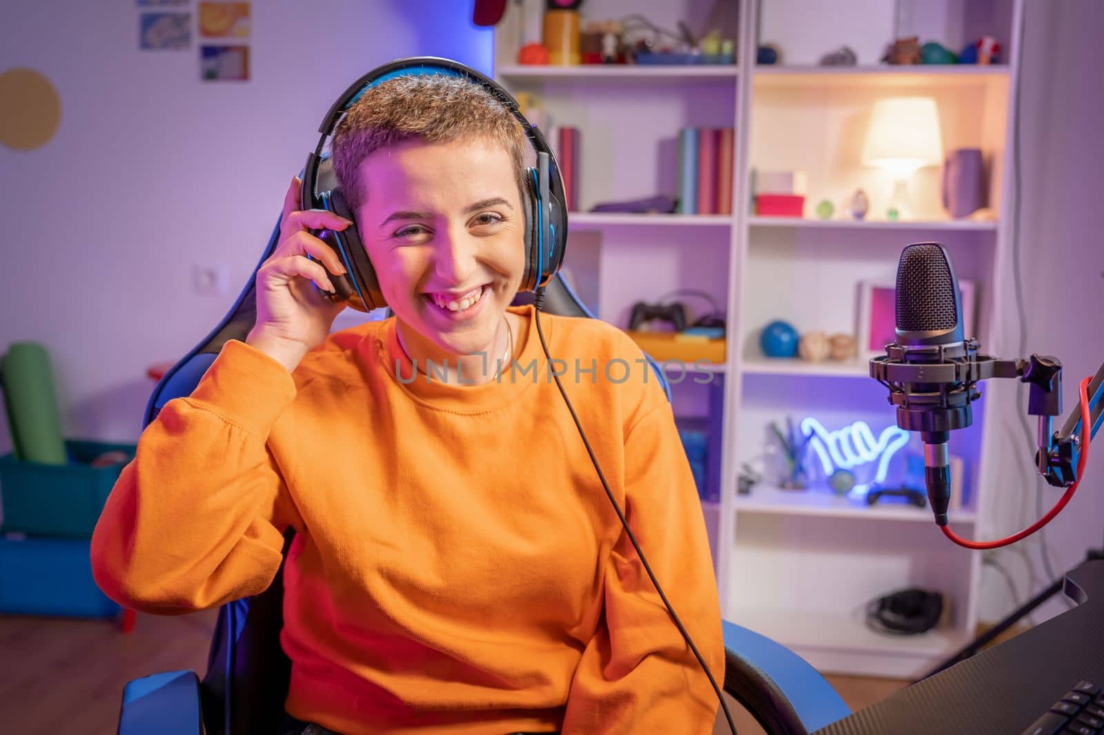 Young short haircut woman playing video games wearing headphones smiling looking and the camera. High quality photo