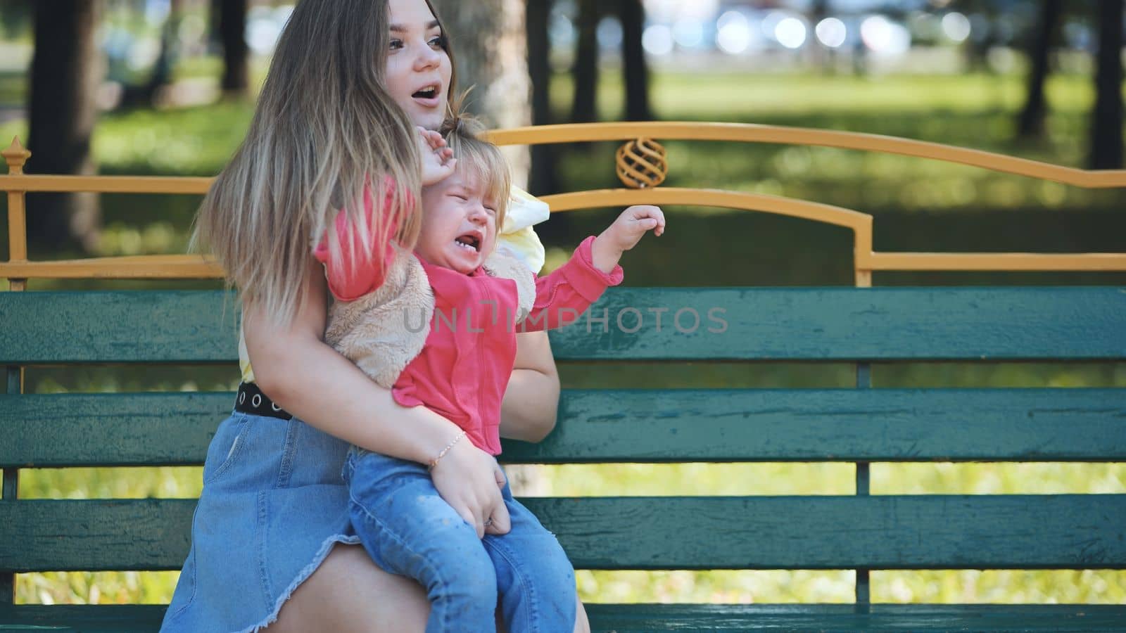 A mother soothes a crying baby in the park