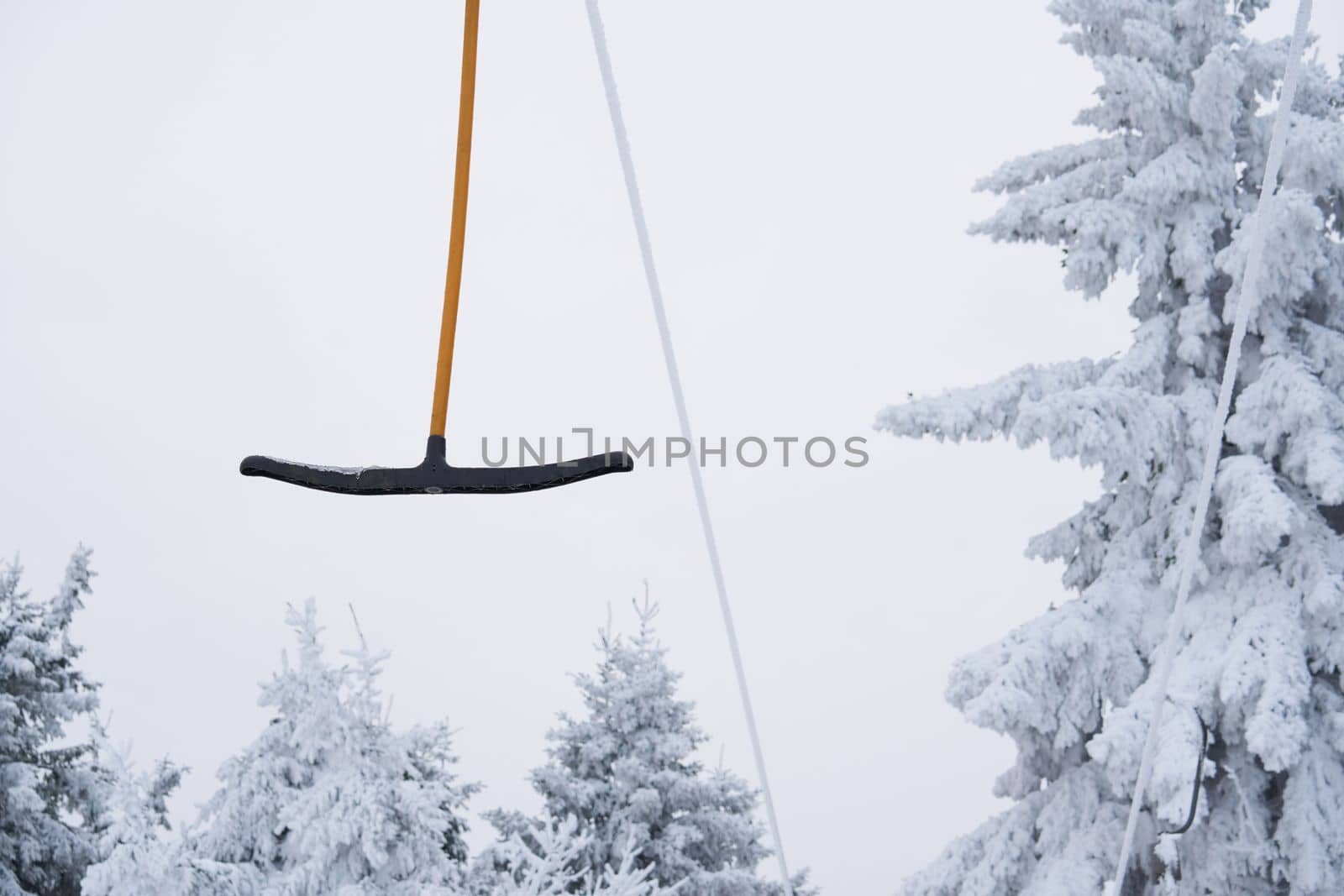 part of a ski lift against the backdrop of a magnificent winter landscape on the Wasserkuppe mountain in Rhen, Hesse, Germany. magical tall and large pines and snowy firs covered with snow and ice. The horizon creates an illusion and merges with the cloudy sky and fog, which covers all the space visible in the distance. by Costin