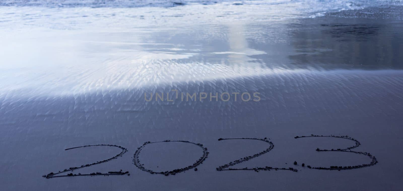 Year 2023 symbol written on black beach sand by Chechotkin