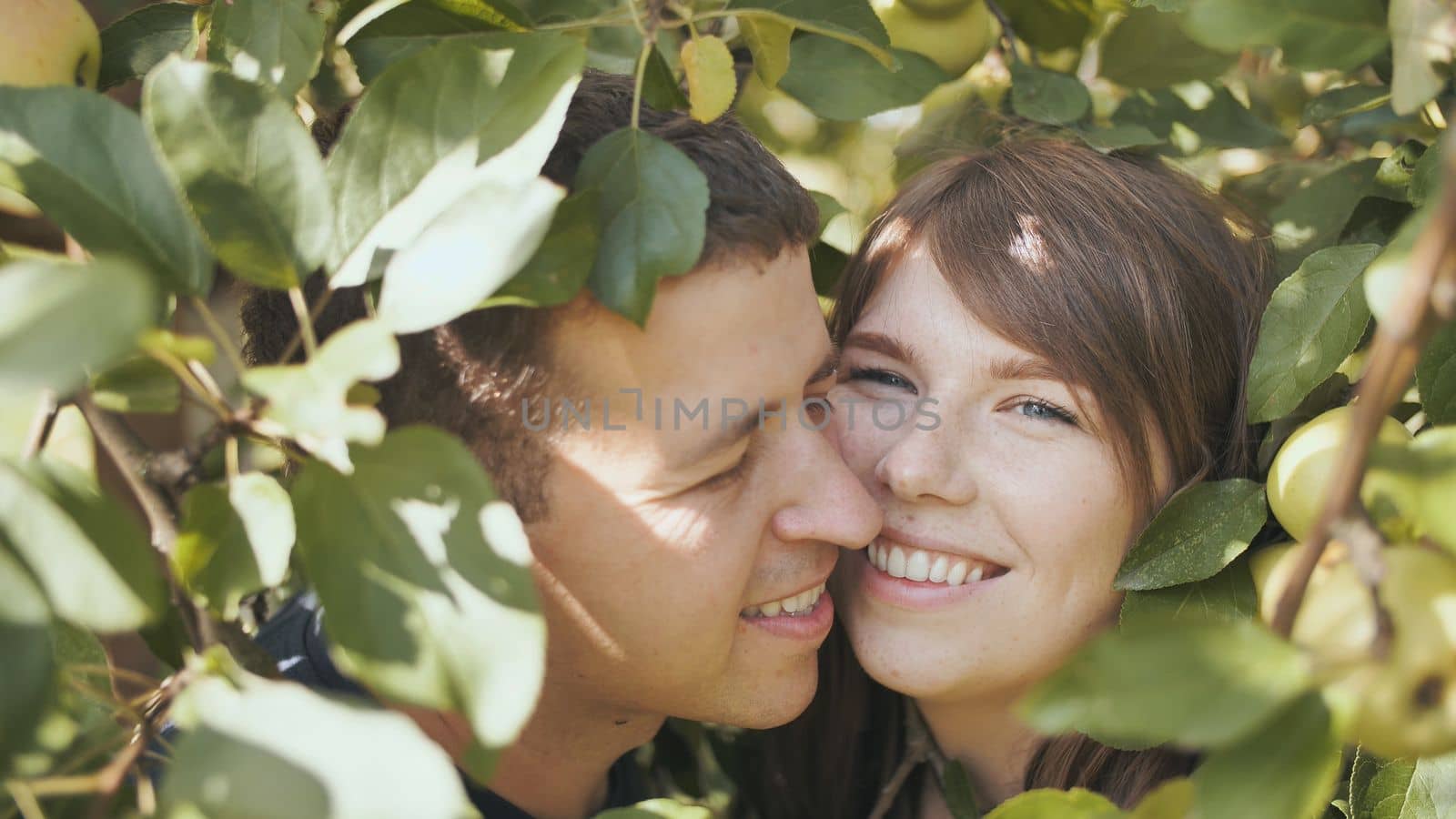 A boy and a girl in love in the branches of an apple tree hugging each other