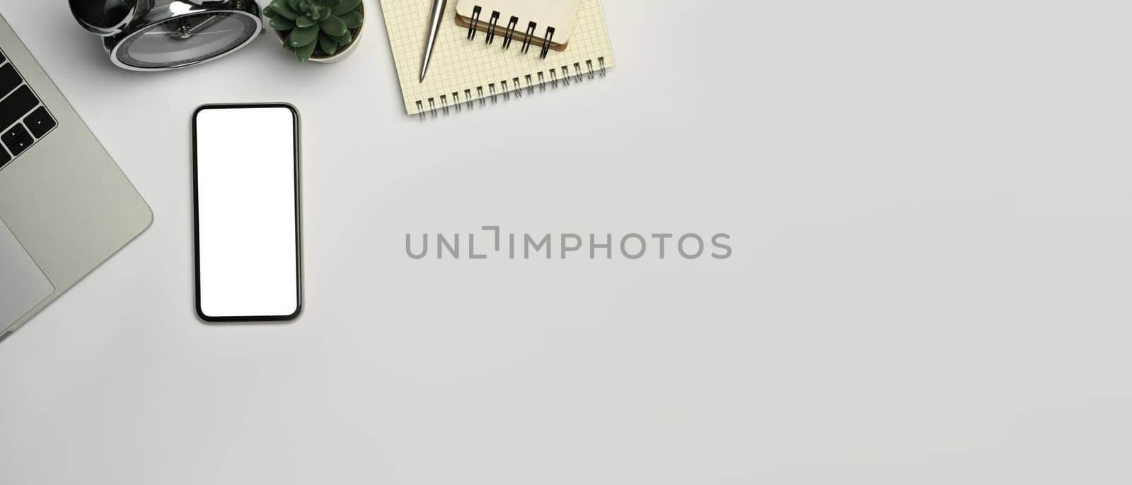 Top view of mobile phone, notepad, potted plant and coffee cup on modern workspace. Blank screen and copy space for your advertise.