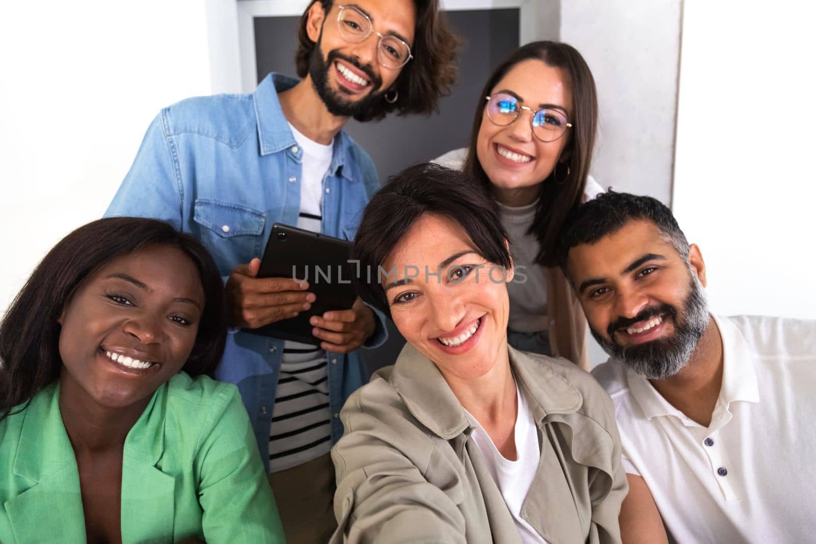 Group of smiling multiracial coworkers take selfie in the office. Social media and business concept.