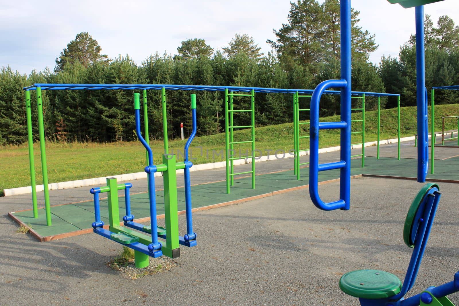 Sports street playground with exercise equipment against the backdrop of a green forest. The concept of a healthy lifestyle. by IronG96