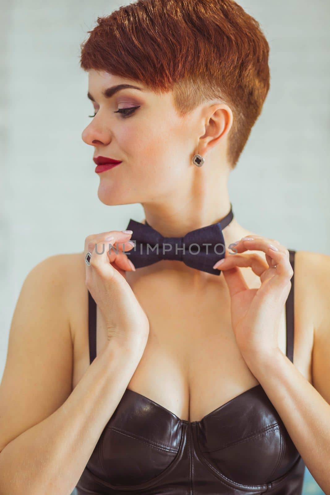 slim woman in a leather dress straightens a butterfly around her neck.
