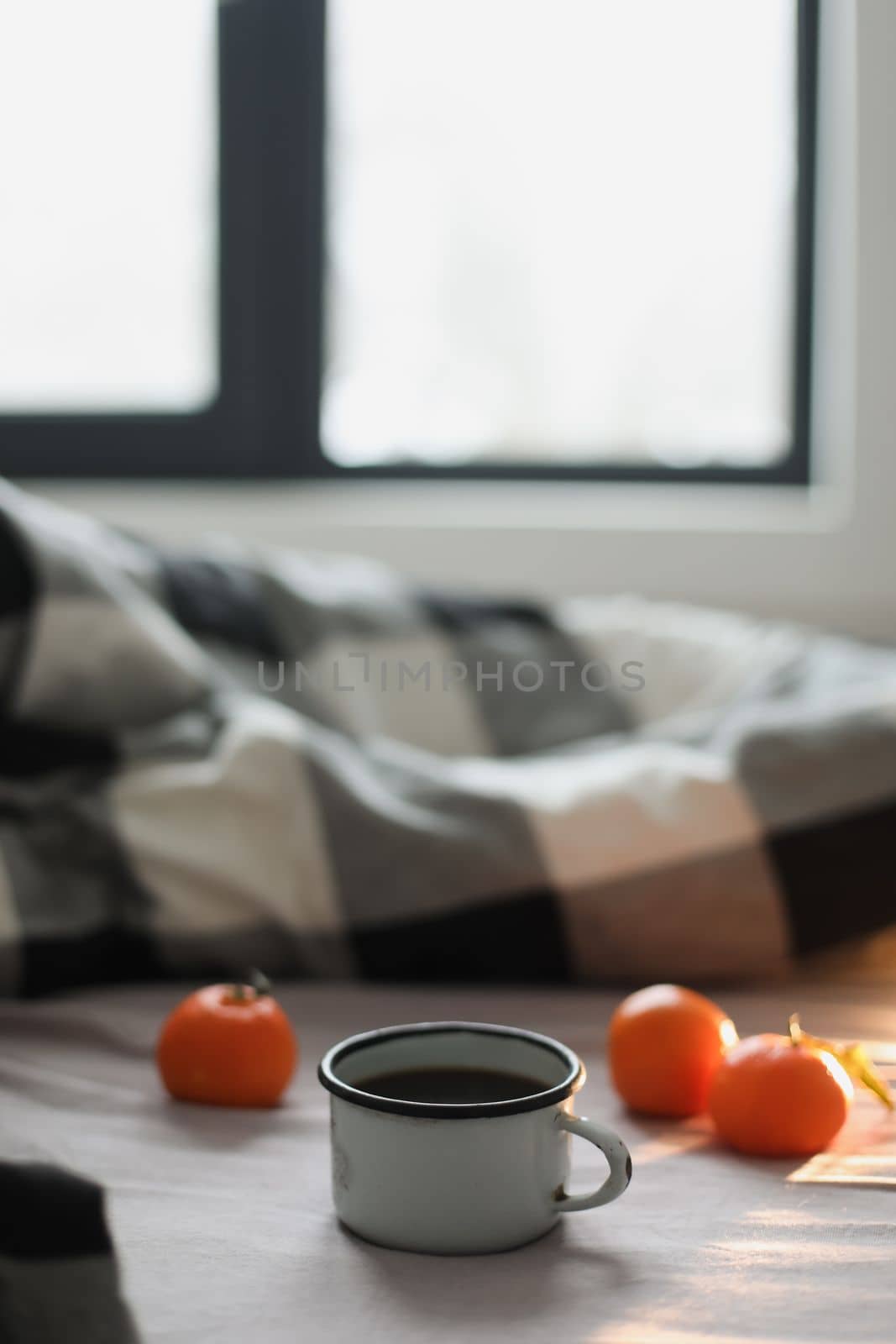 Winter cozy concept. Cup with coffee and tangerines on the bed. Copy space. Flat lay, top view.