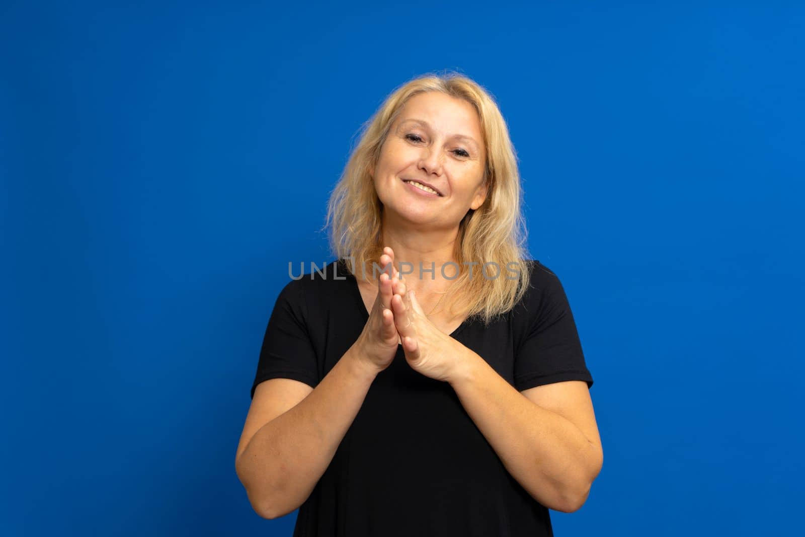 Pretty blonde caucasian woman feeling happy and successful, smiling and applauding, saying congratulations with a clap against blue colored wall