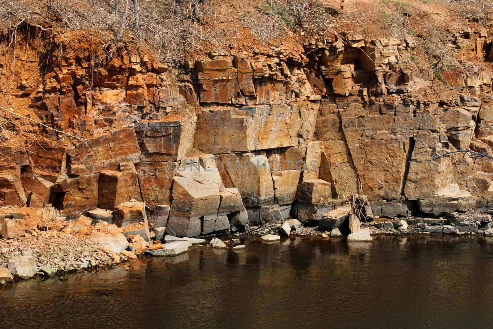 Red-yellow rocky cliff above the river. The concept of mining by IronG96