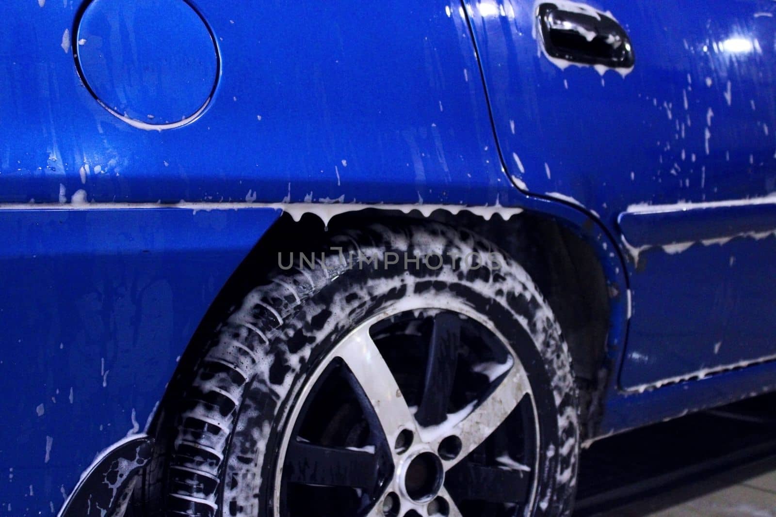 The back of a blue car in defocus close-up at a car wash. Side view. The concept of ecology and environmental pollution by IronG96