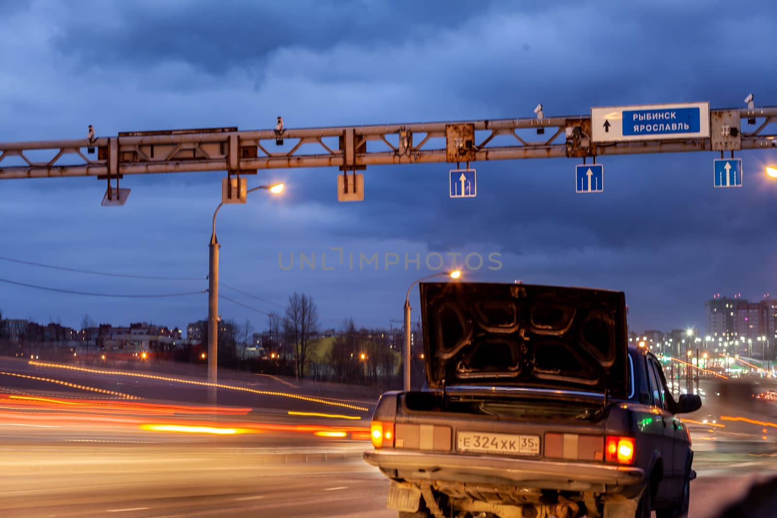 29.11.2022, Cherepovets, Russia.A large automobile bridge on which cars drive at night. There is a broken car and an emergency sign on the bridge. A bridge with large columns and lighting.