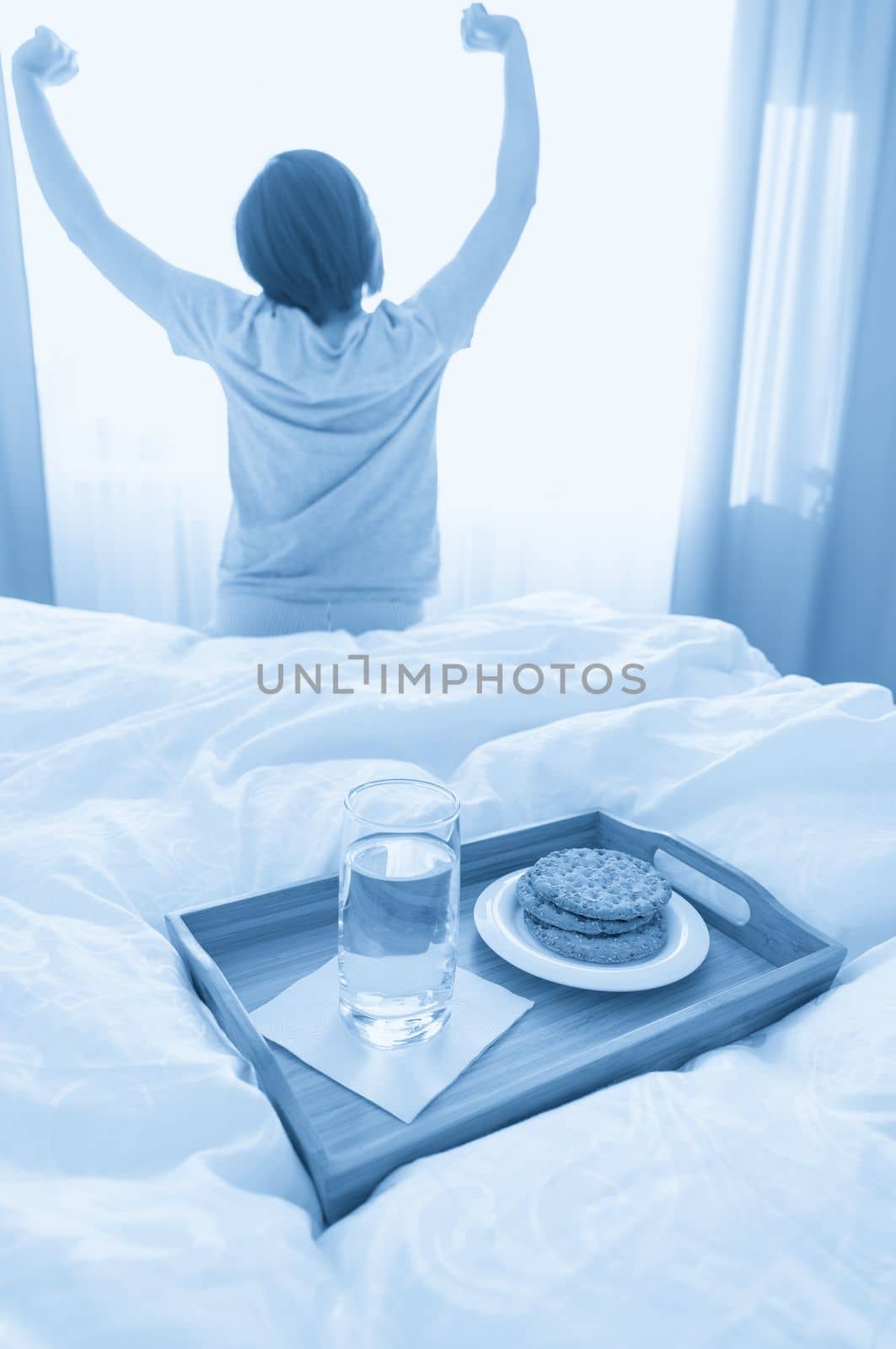 Diet breakfast on a bed with woman stretching on background by Mariakray