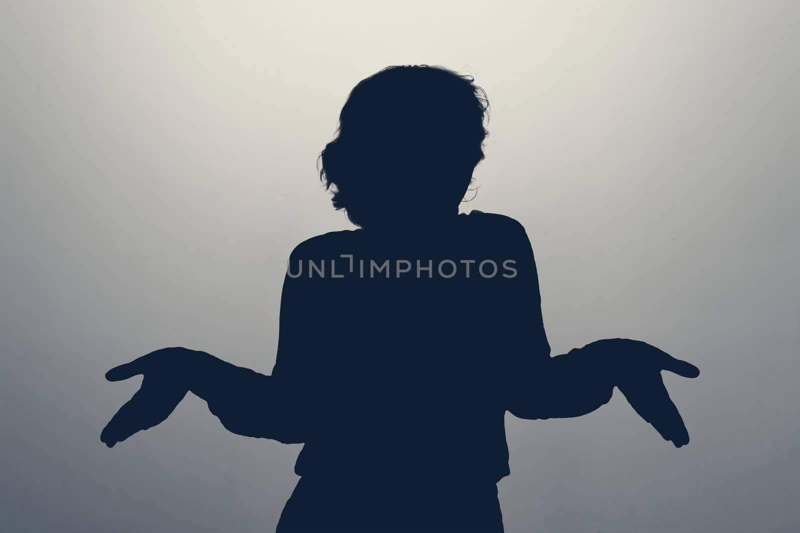 Unknown female person shrug her hands having clueless expression. silhouette photo