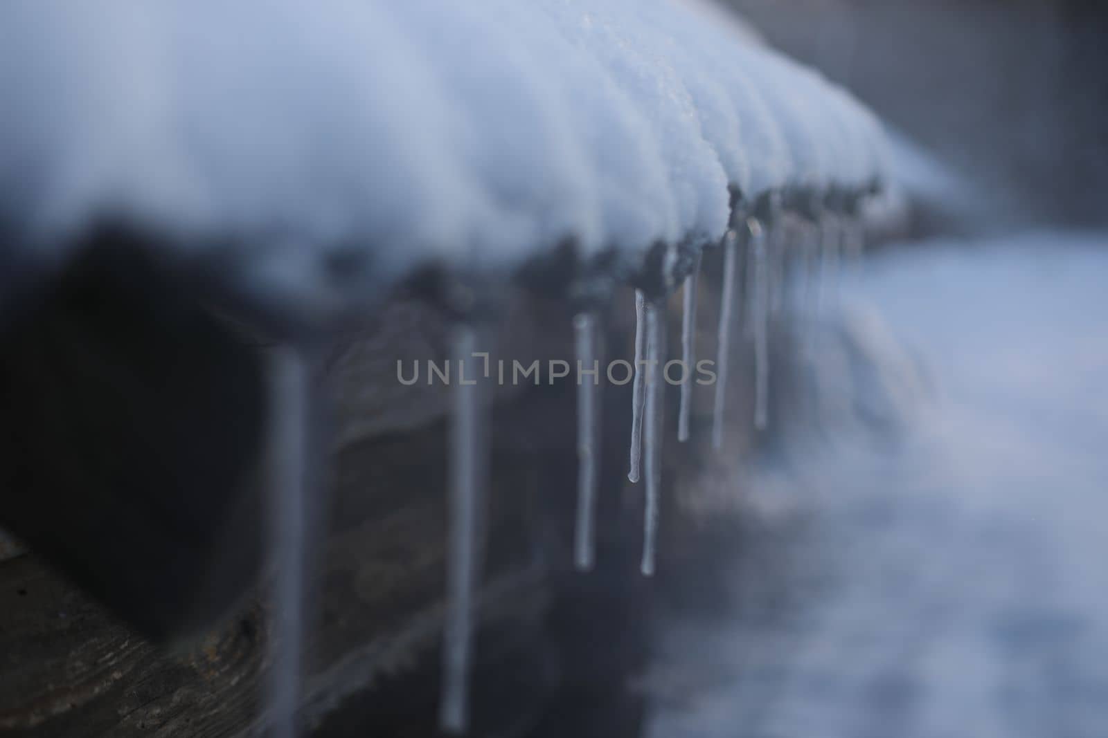 Spring background with icicles melting in the sun. Icicles close-up. Snow melting. The beginning of the warm season, the end of winter. Rustic scene in early spring.