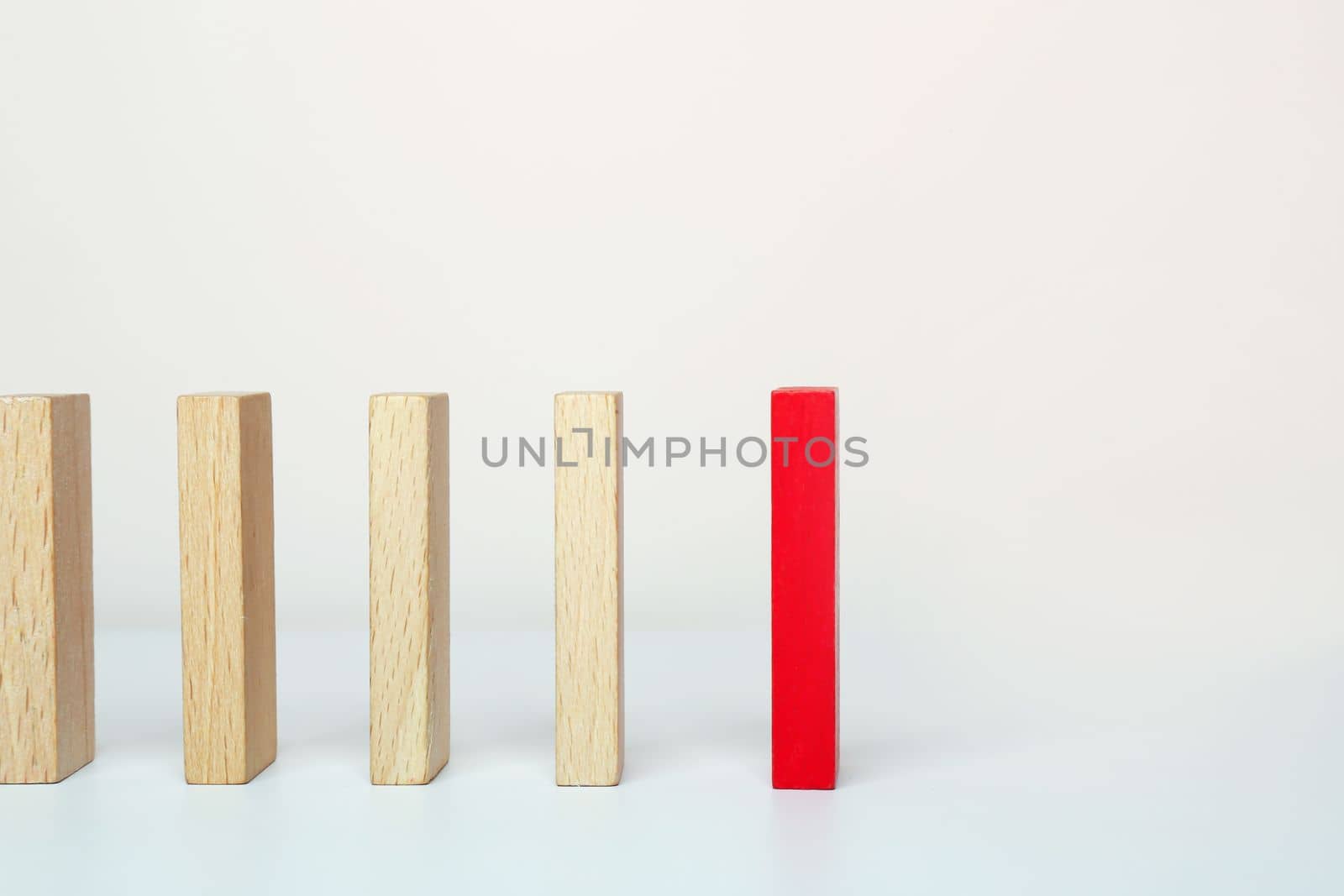 One red wooden block between the wooden block on white background. Be different concept.
