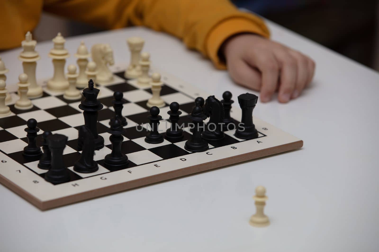 Chess board on table in front of school boy thinking of next move, tournament
