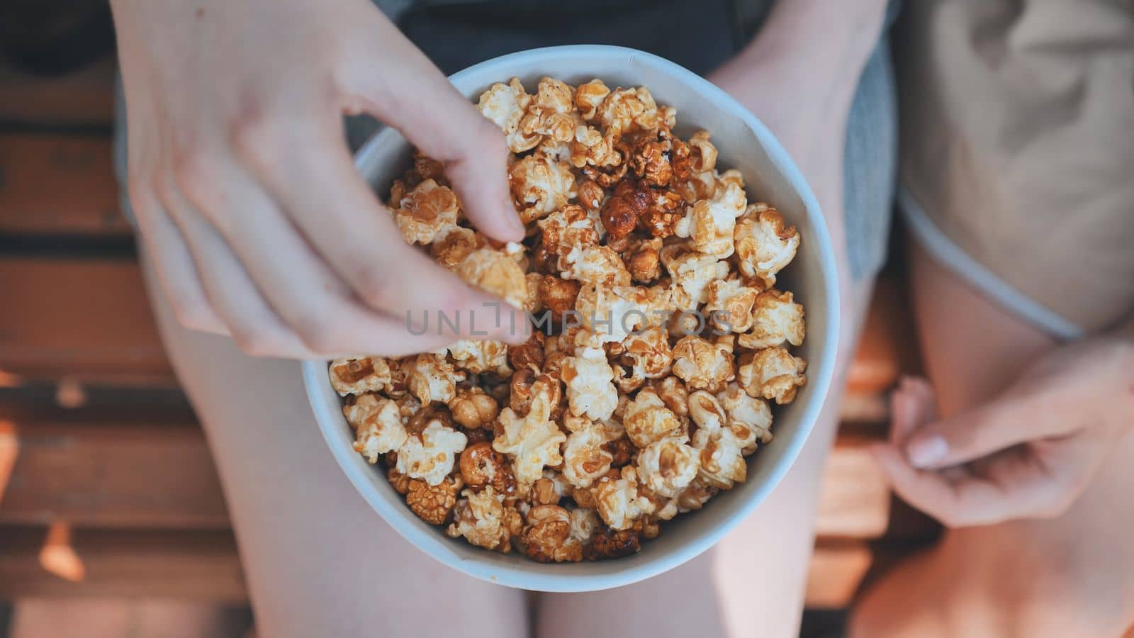 Friends eating popcorn on the street. Close-up of hands