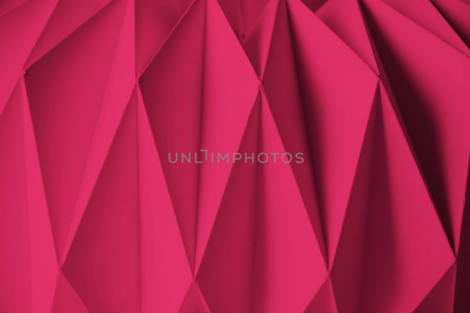 Macro Viva Magenta image of paper folded in geometric shapes, three-dimensional effect, abstract background. Out of focus. Trendy color 2023 Viva Magenta. High quality photo