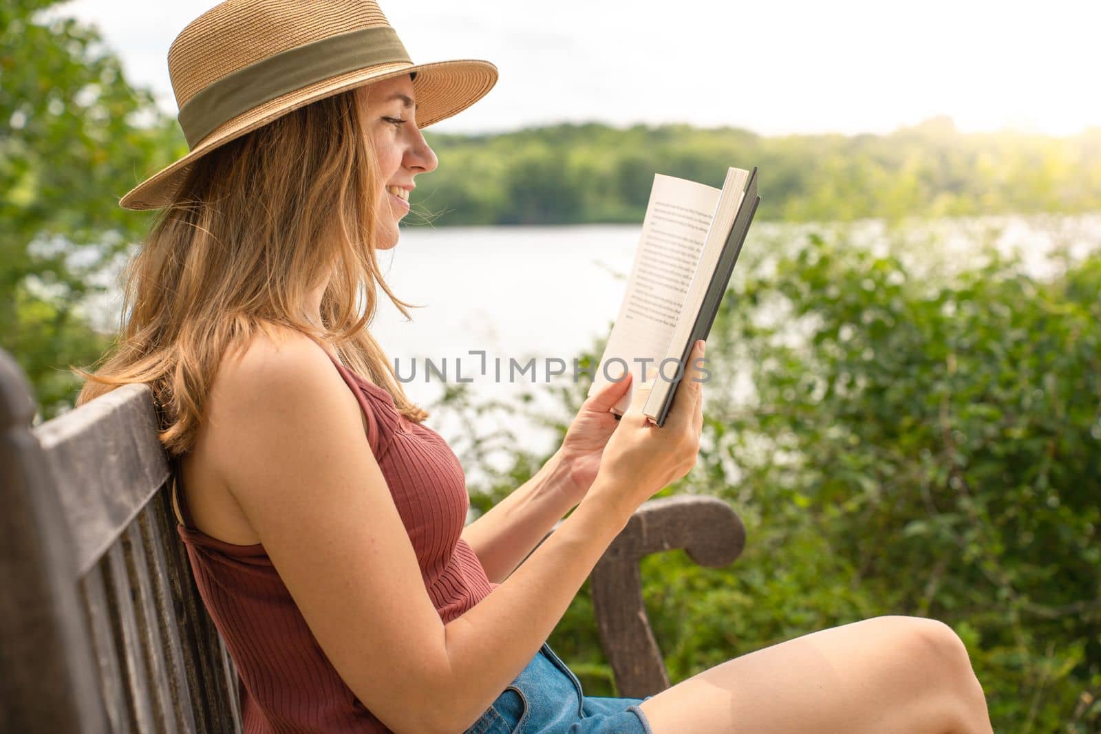 Young woman with book sitting on chair in green garden terrace. High quality photo