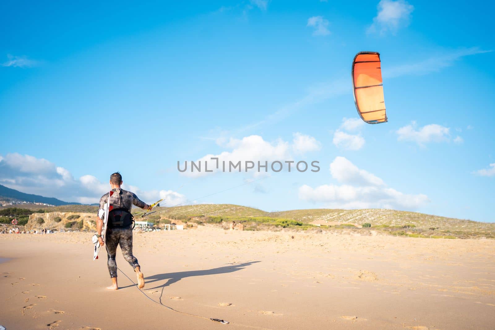 Portrait wave kitesurfer walking beach with his board and kite by andreonegin
